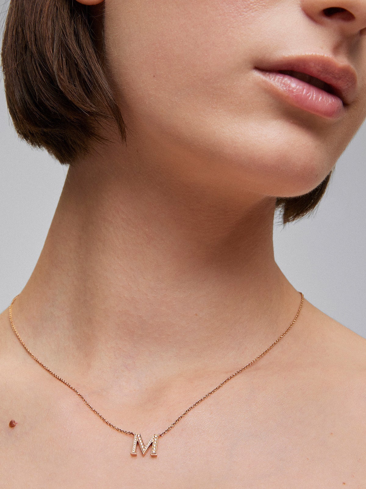 Colgante de oro rosa de 18K con letra M y 16 diamantes en talla brillante con un total de 0,07 cts