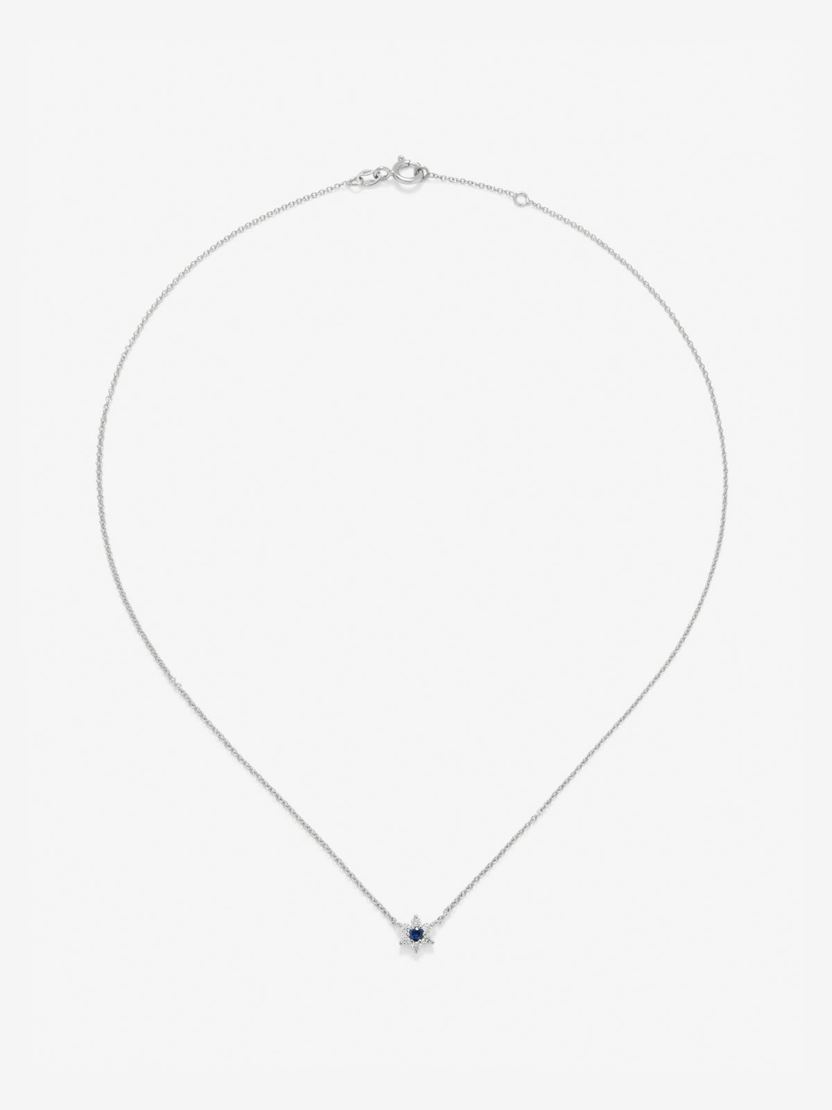 Colgante de oro blanco de 18K con zafiro azul en talla brillante de 0,1 cts y 6 diamantes en talla brillante con un total de 0,12 cts en forma de estrella
