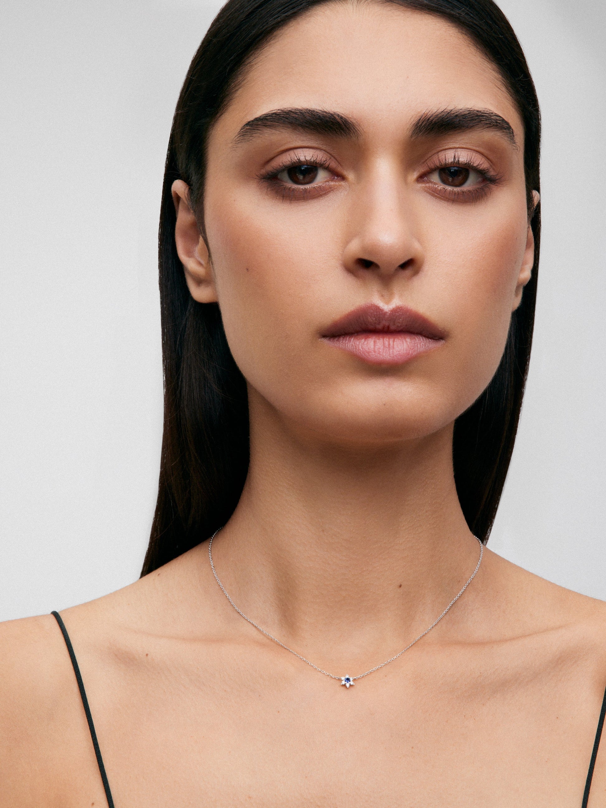 Colgante de oro blanco de 18K con zafiro azul en talla brillante de 0,1 cts y 6 diamantes en talla brillante con un total de 0,12 cts en forma de estrella