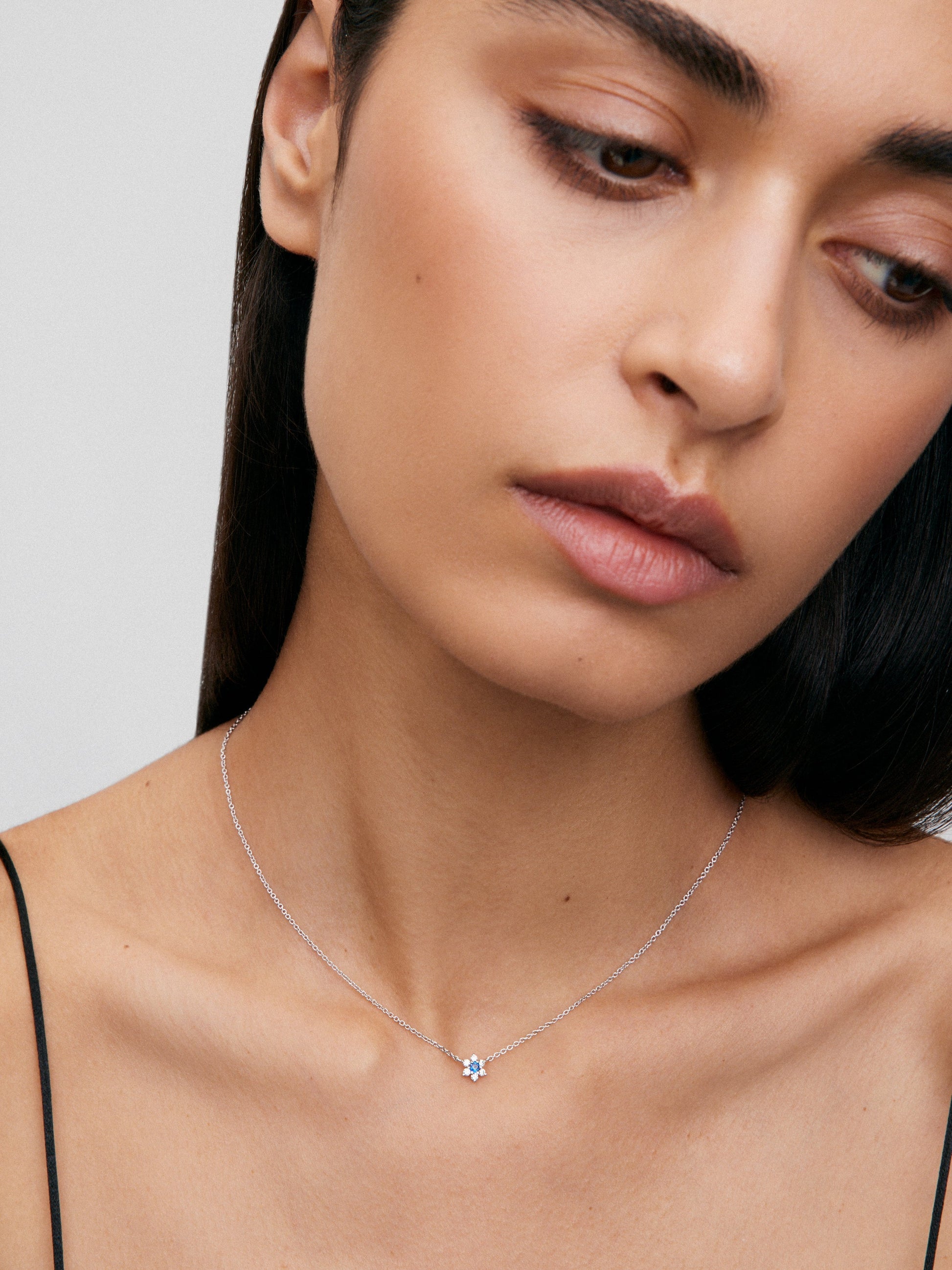 Colgante de oro blanco de 18K con zafiro azul en talla brillante de 0,1 cts y 6 diamantes en talla brillante con un total de 0,12 cts en forma de estrella