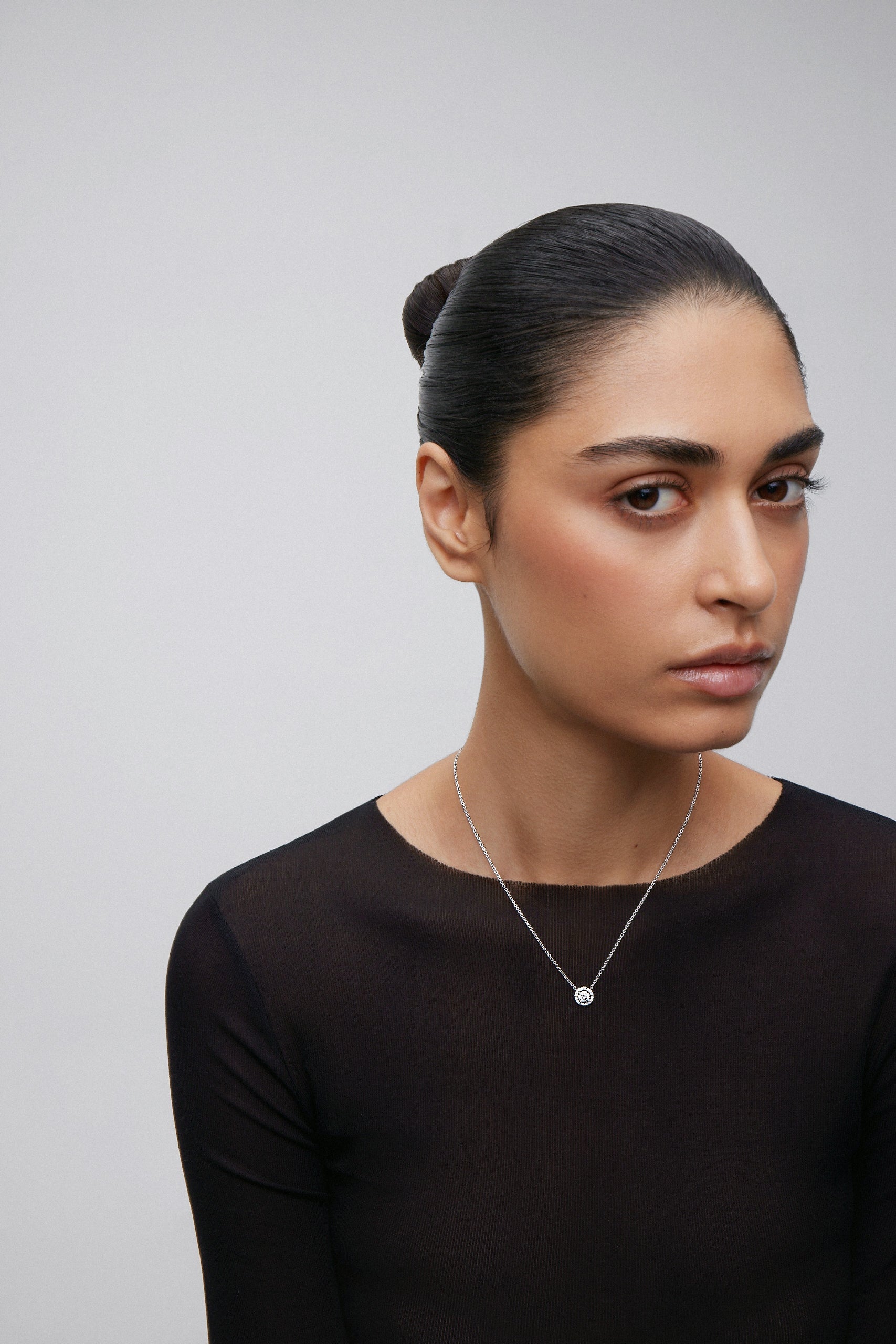 Colgante cadena de oro blanco de 18K con diamante solitario y orla de diamantes