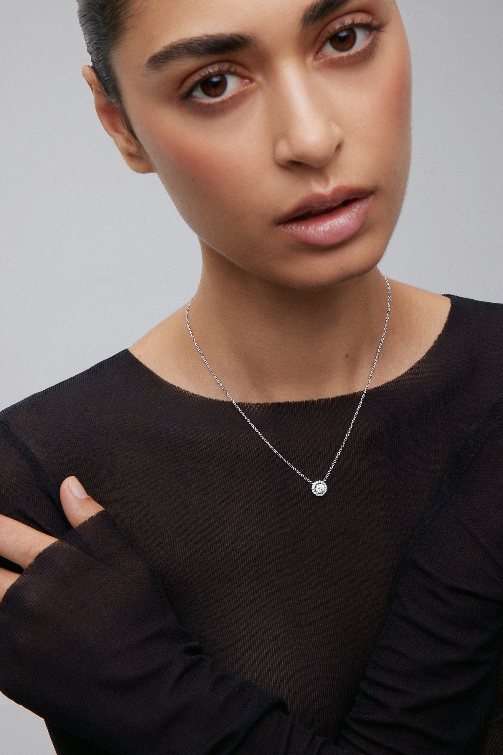 Colgante cadena de oro blanco de 18K con diamante solitario y orla de diamantes