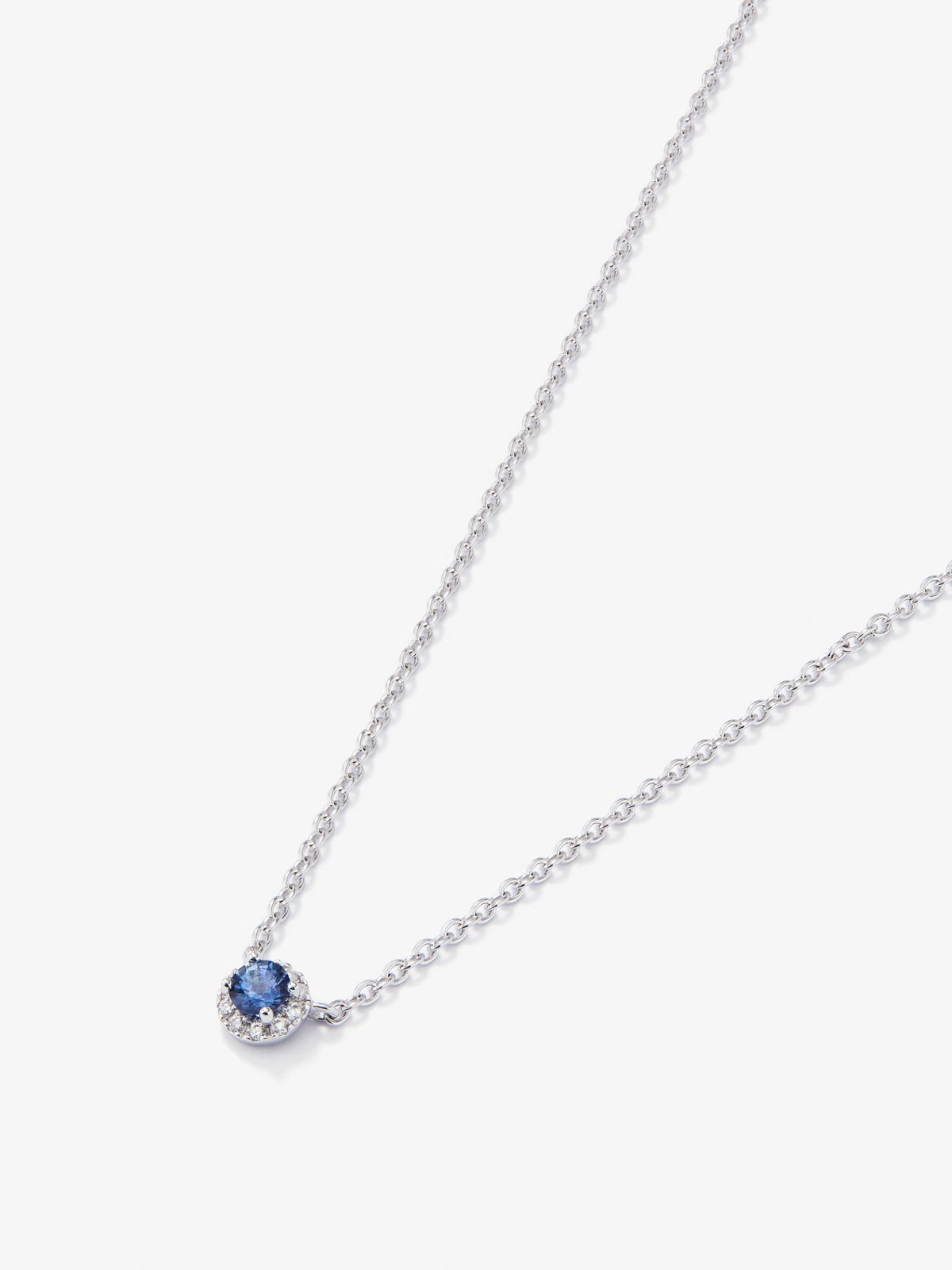 Colgante de oro blanco de 18K con zafiro azul en talla brillante de 0,23 cts y orla de 10 diamantes en talla brillante con un total de 0,07 cts