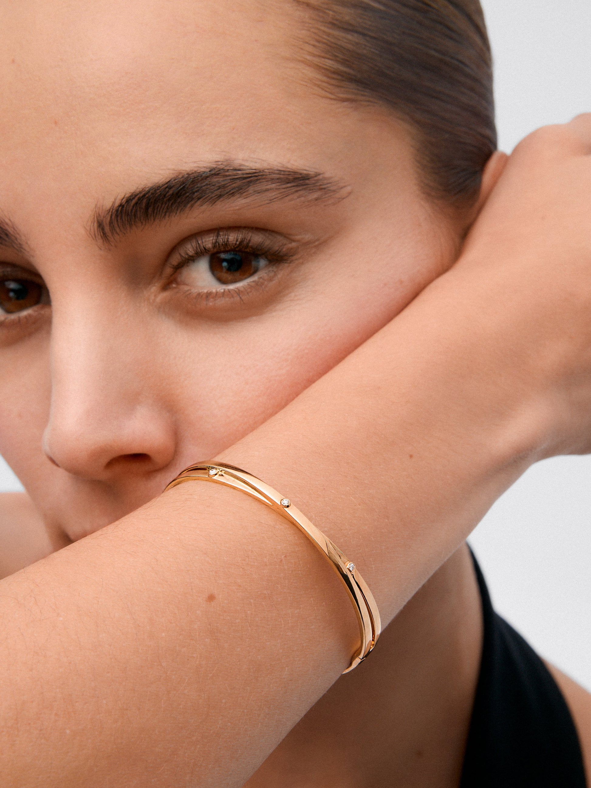 Pulsera rígida cruzada de oro amarillo de 18K con 3 diamantes en talla brillante con un total de 0,04 cts