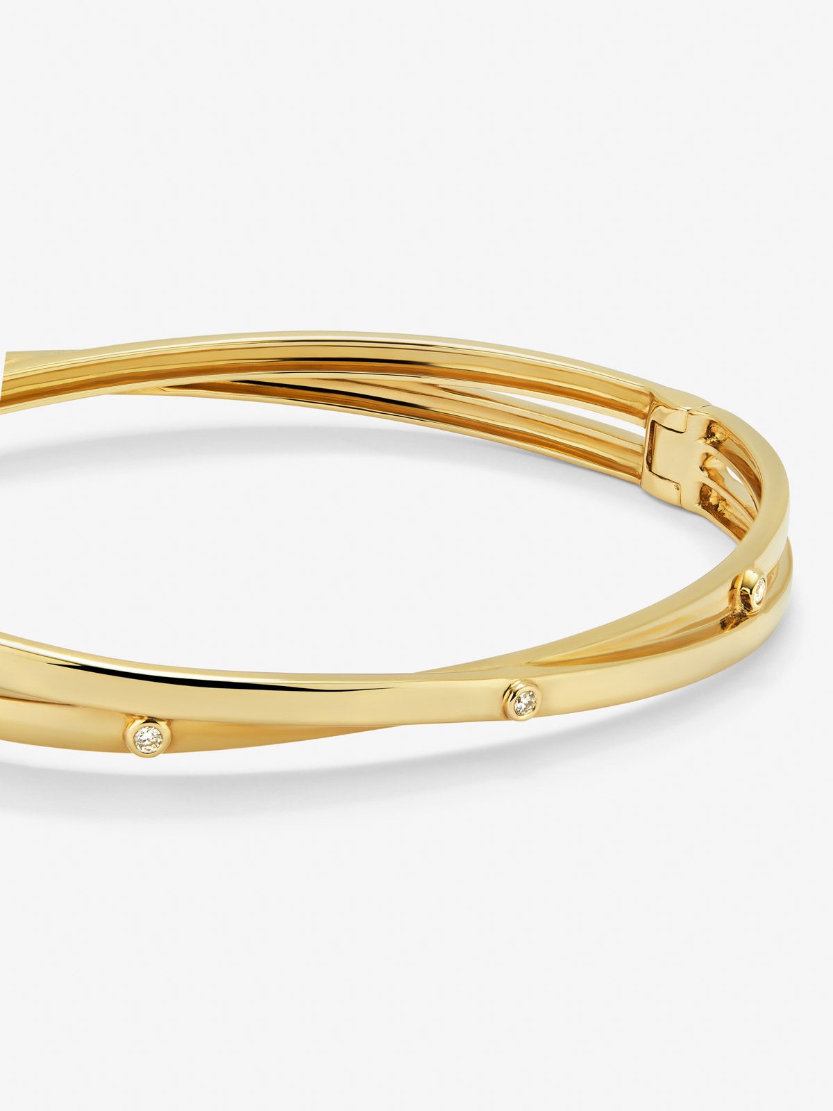 Pulsera rígida cruzada de oro amarillo de 18K con 3 diamantes en talla brillante con un total de 0,04 cts
