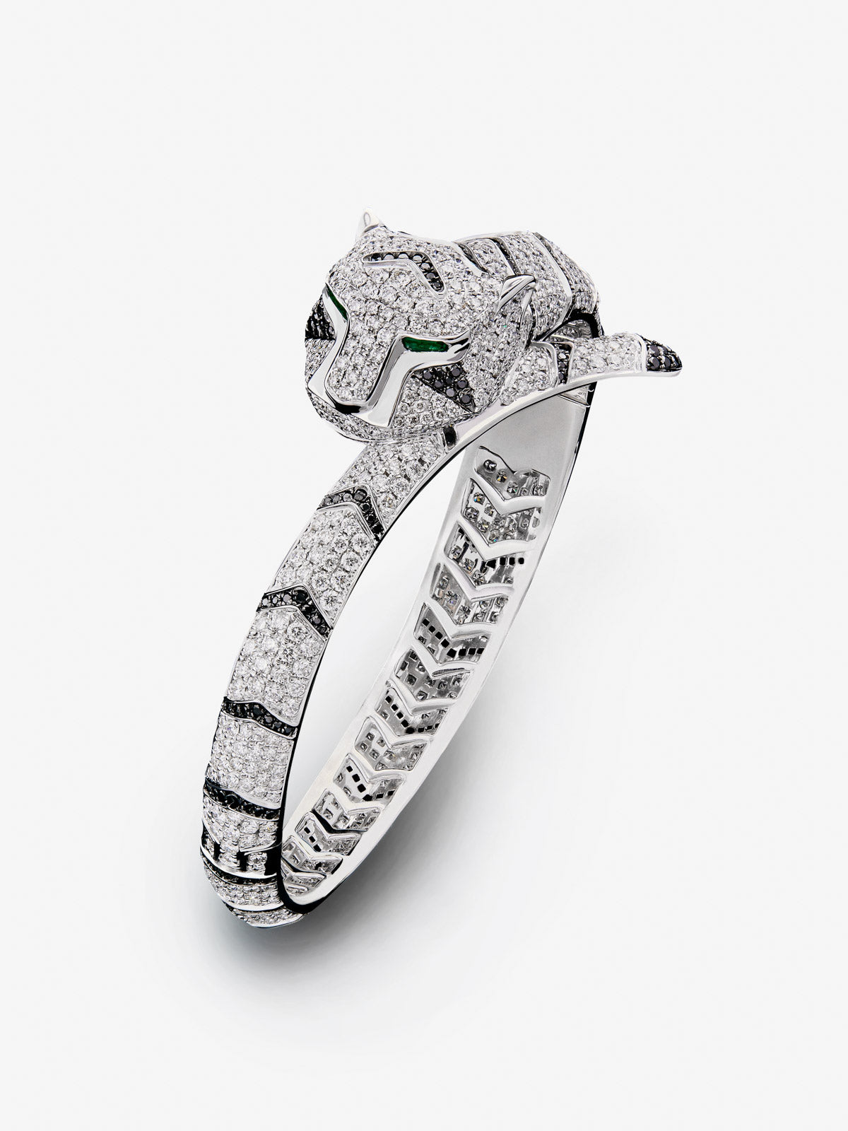 Pulsera rígida con forma de tigre en oro blanco de 18K con diamantes blancos y negros en talla brillante con un total de 9,66 cts y esmeraldas en talla trapecio con un total de 0,13 cts