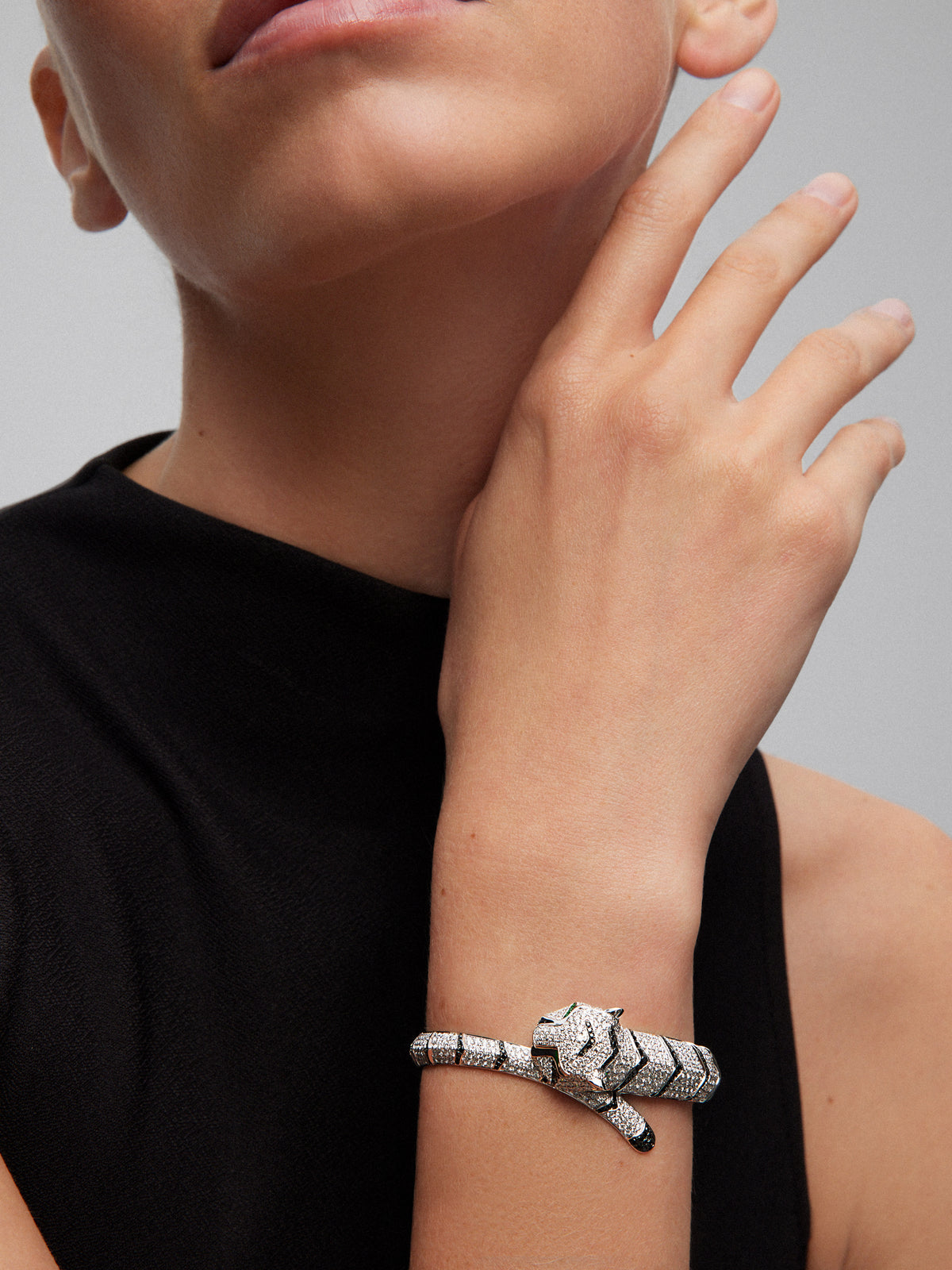 Pulsera rígida con forma de tigre en oro blanco de 18K con diamantes blancos y negros en talla brillante con un total de 9,66 cts y esmeraldas en talla trapecio con un total de 0,13 cts