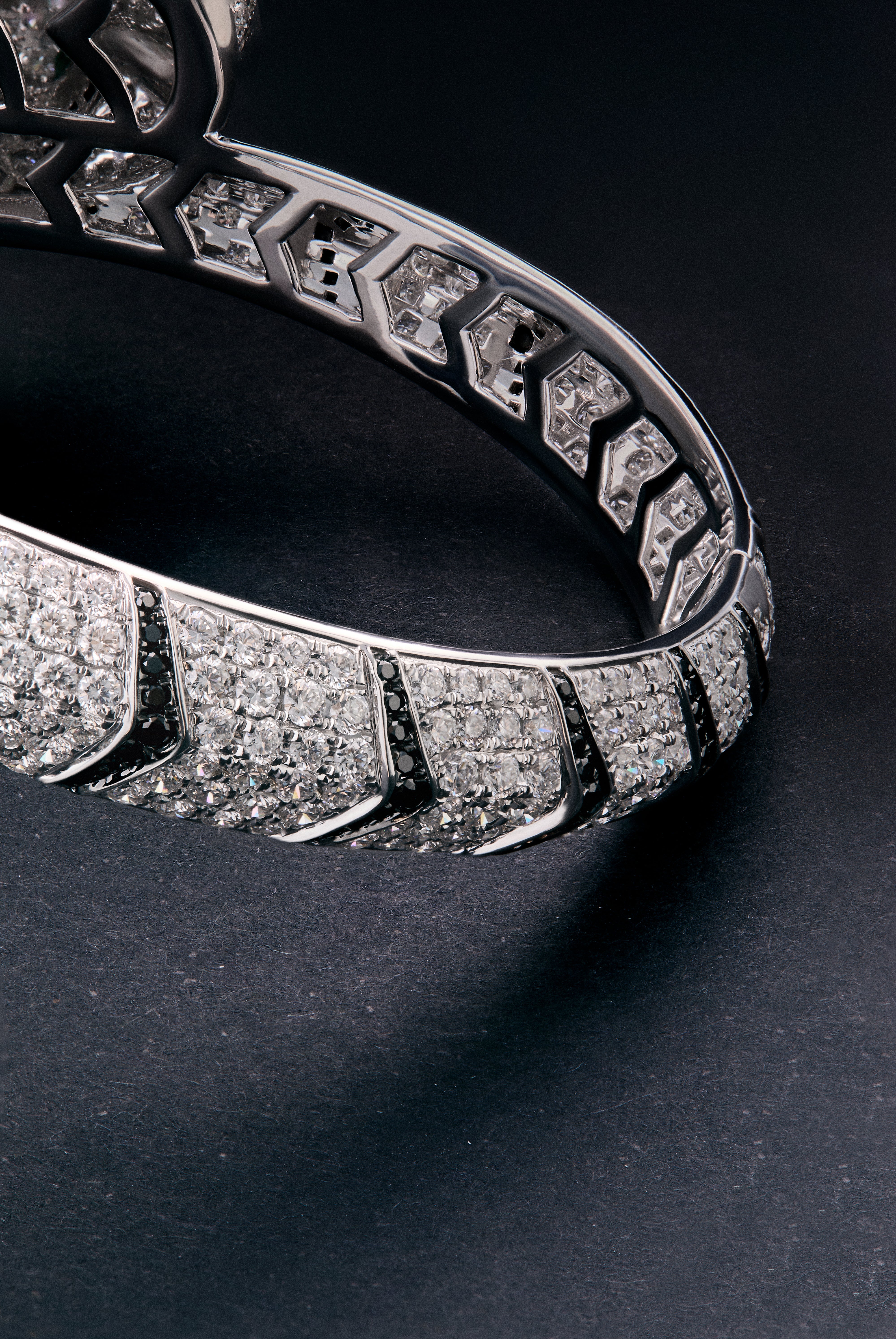 Pulsera rígida con forma de tigre en oro blanco de 18K con diamantes blancos y negros en talla brillante con un total de 9,66 cts y esmeraldas en talla trapecio con un total de 0,13 cts 