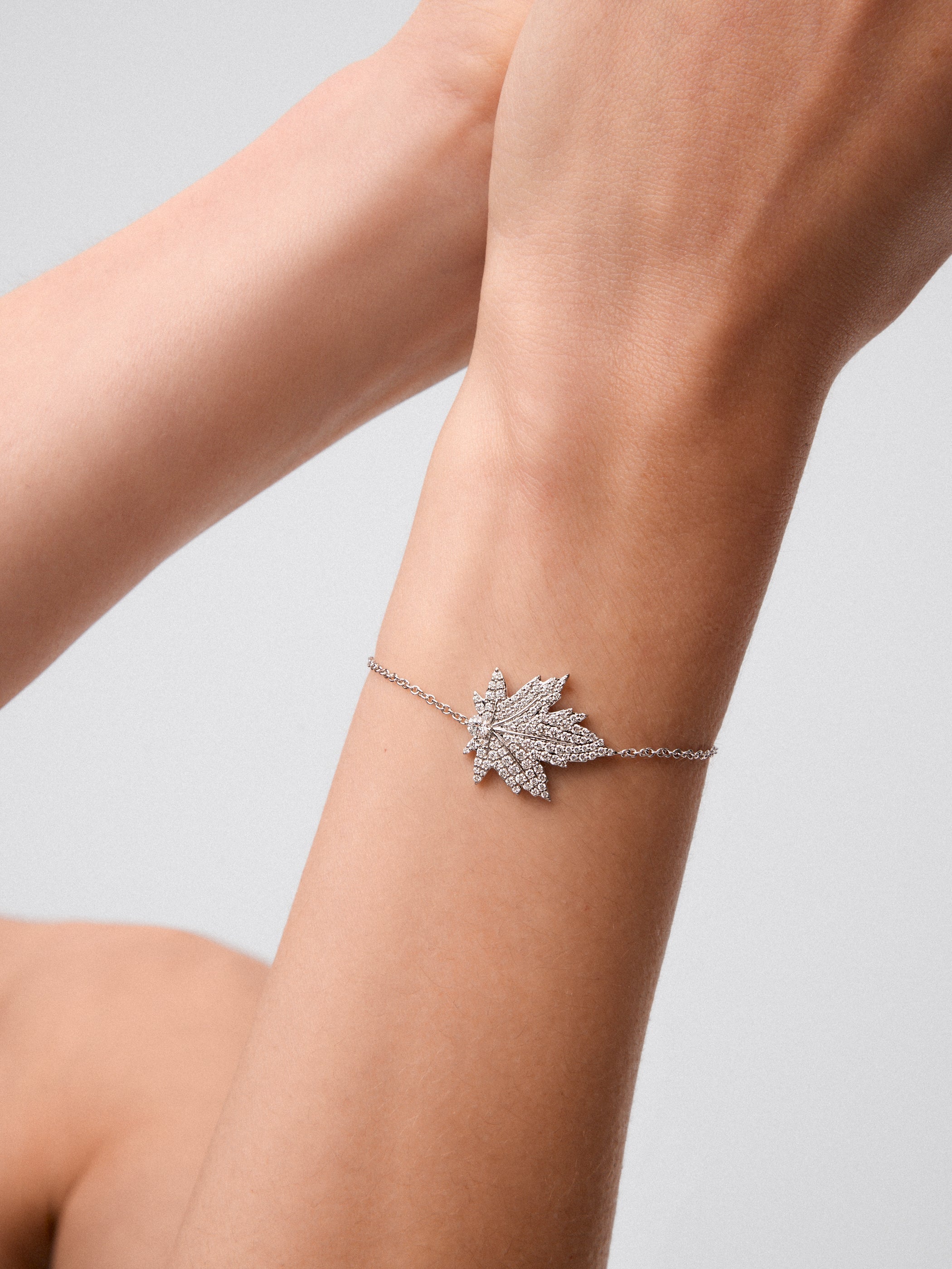 Pulsera de oro blanco de 18K con diamante central en talla brillante de 0,14 cts, pavé de diamantes y forma de hoja de arce