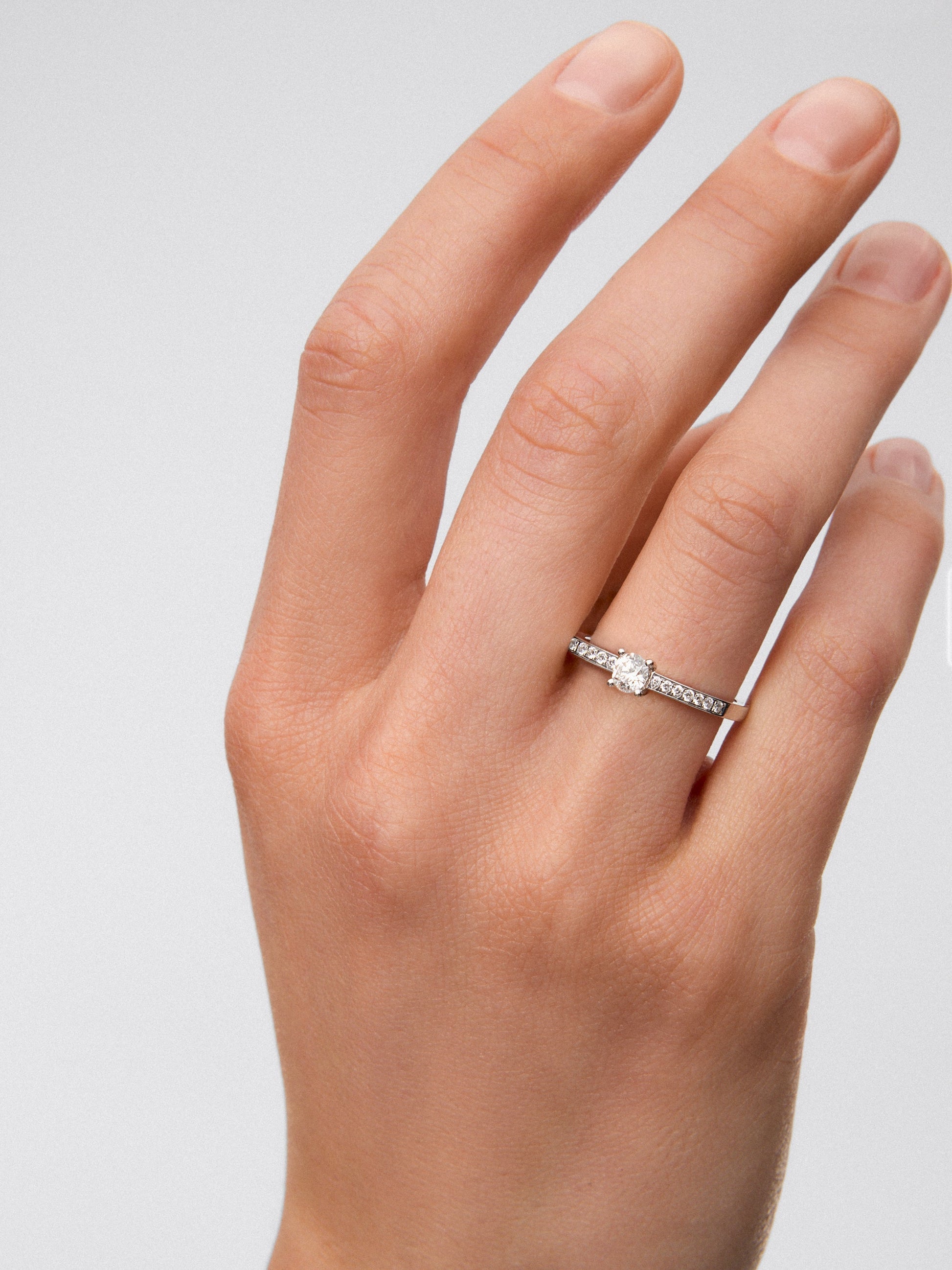 Anillo solitario de oro blanco de 18K con diamante central en talla brillante de 0,3 cts y brazo de 18 diamantes en talla brillante con un total de 0,13 cts