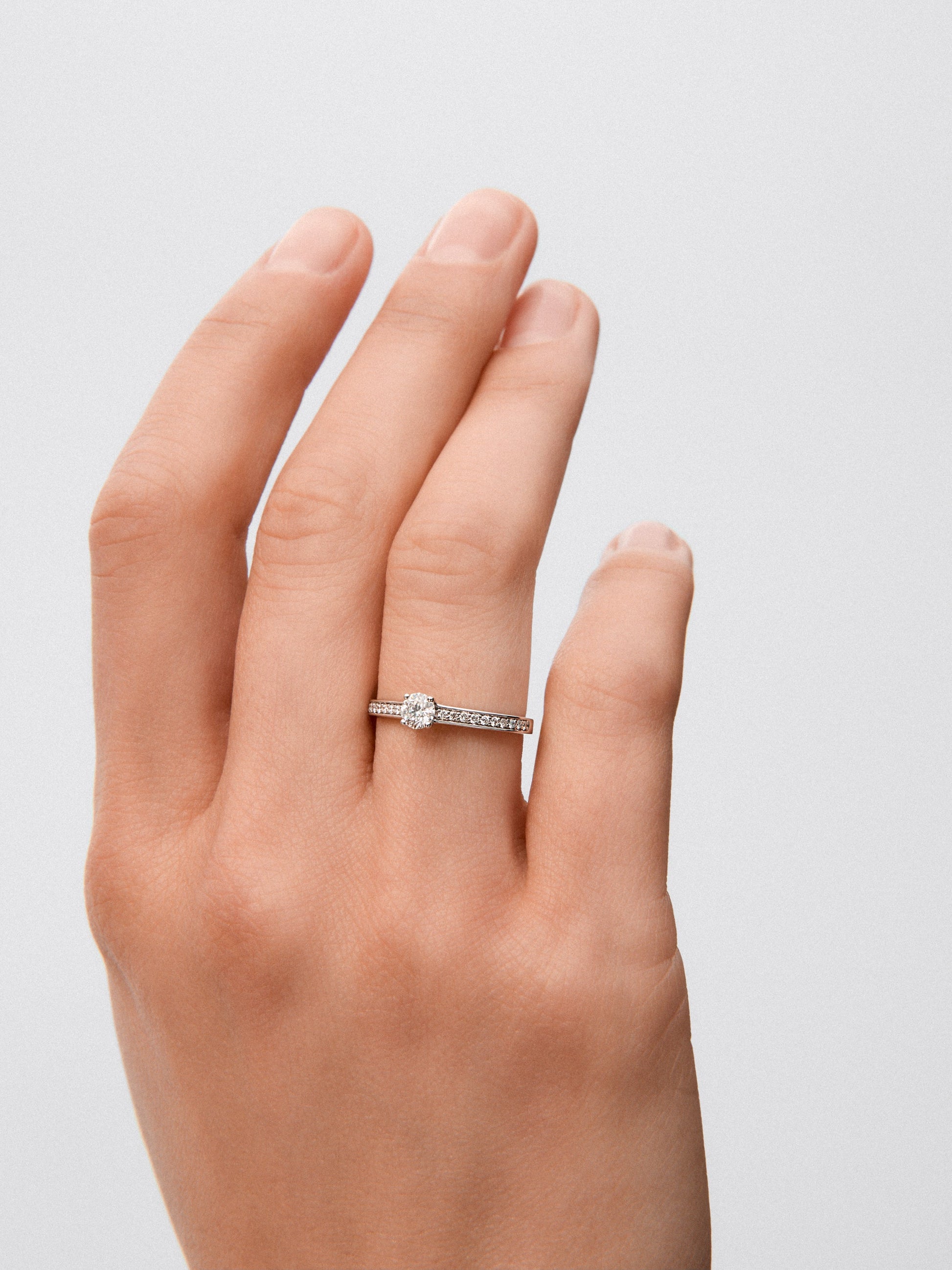 Anillo solitario de oro blanco de 18K con diamante central de 0,25 cts y brazo de diamantes en talla brillante