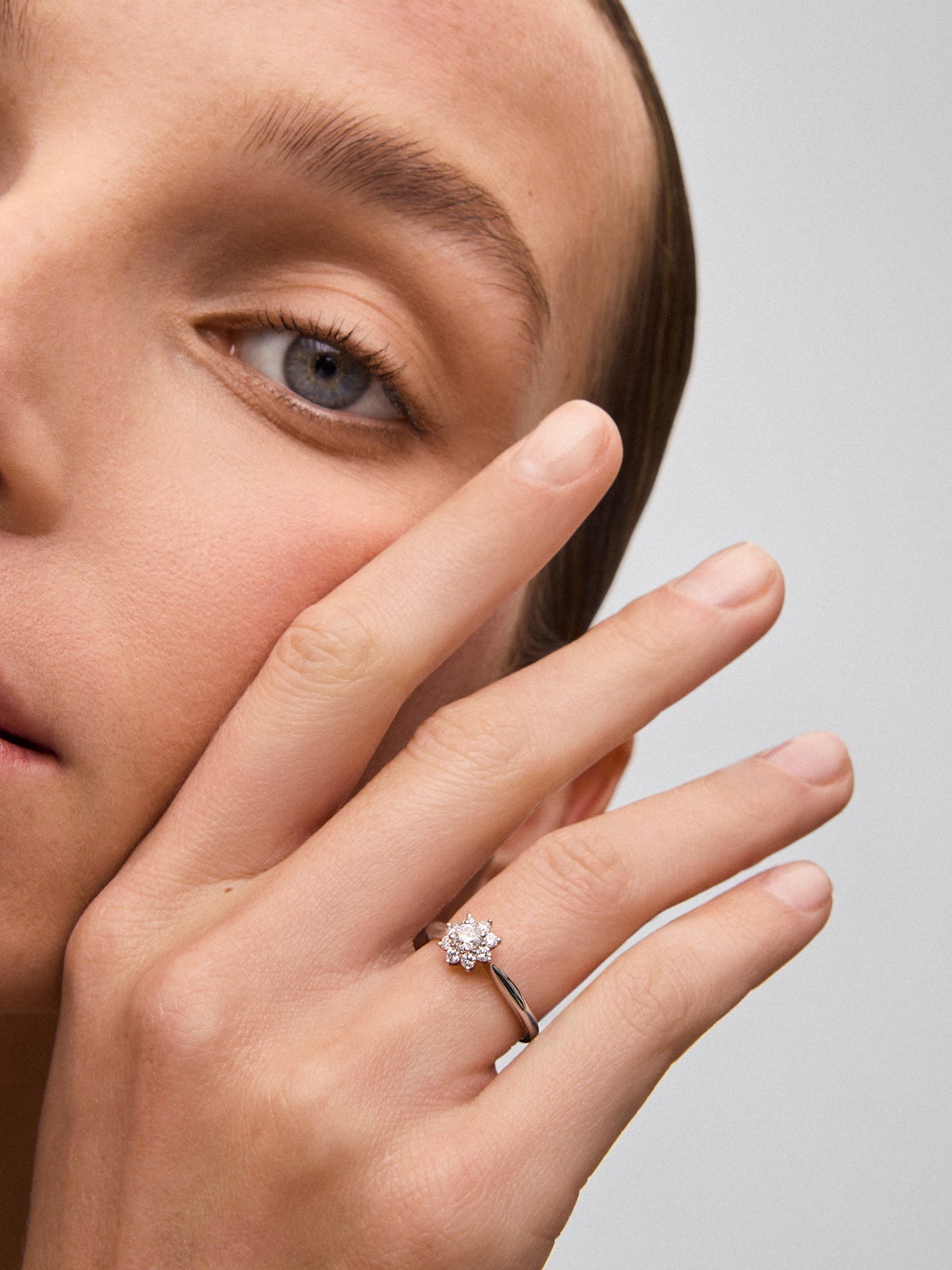 Anillo de oro blanco de 18K con diamante central en talla brillante de 0,2 cts y orla de 8 diamantes en talla brillante con forma de estrella