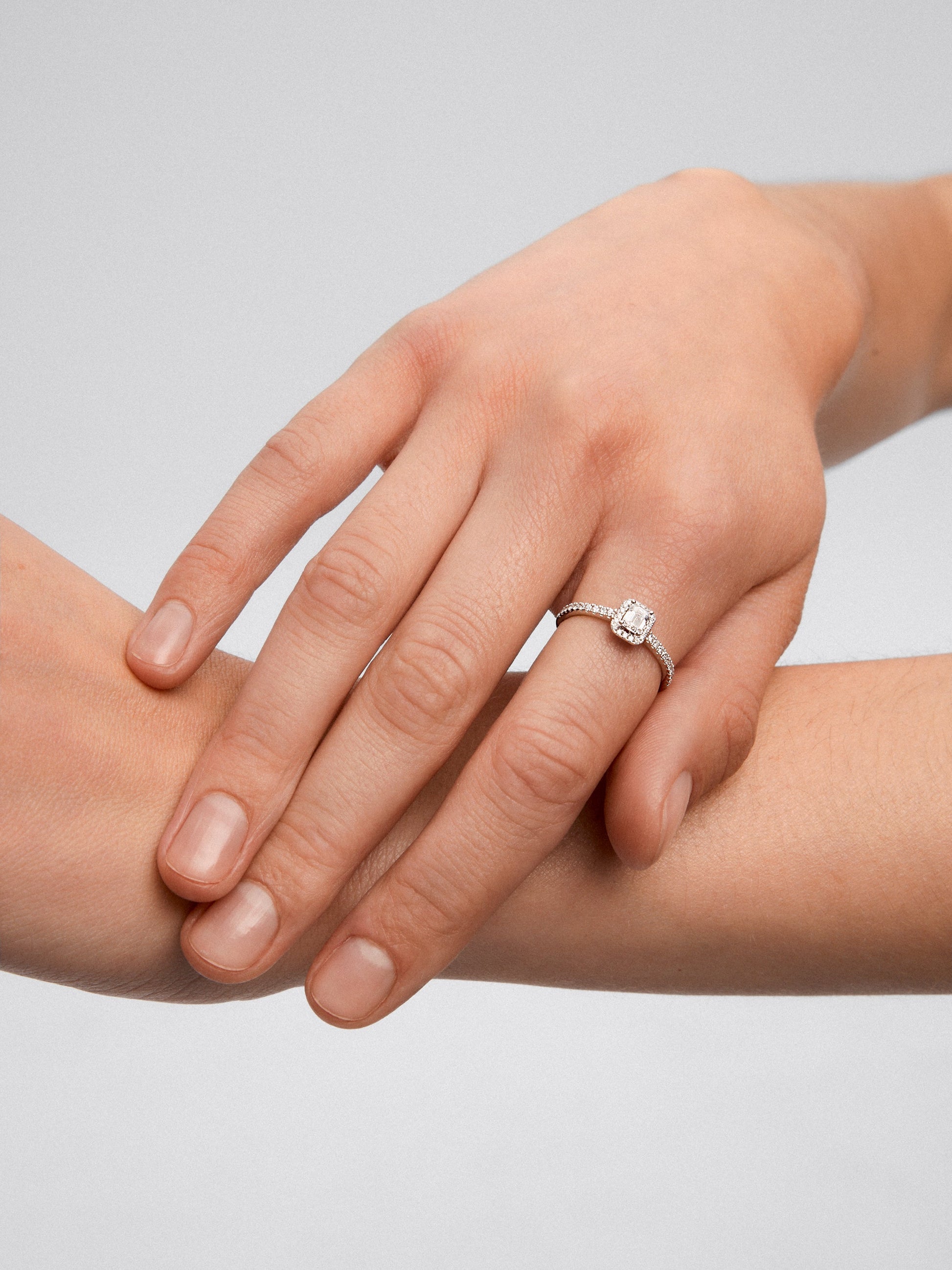 Anillo de oro blanco de 18K con diamante en talla esmeralda de 0,30 cts y orla de diamantes en talla brillante con un total de 0,19 cts