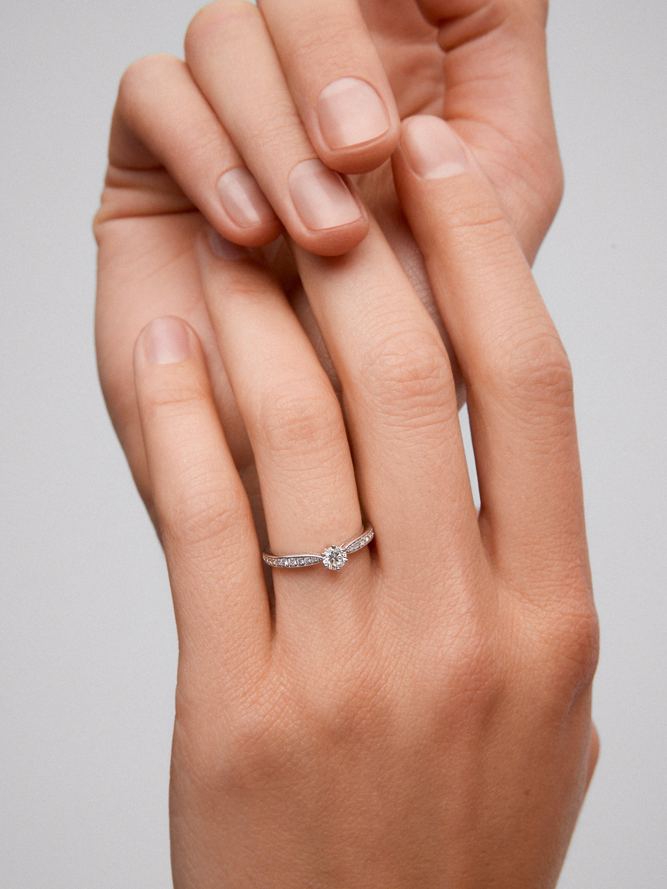 Anillo solitario de oro blanco de 18K con diamante central en talla brillante de 0,20 cts y diamantes en talla brillante con un total de 0,10 cts