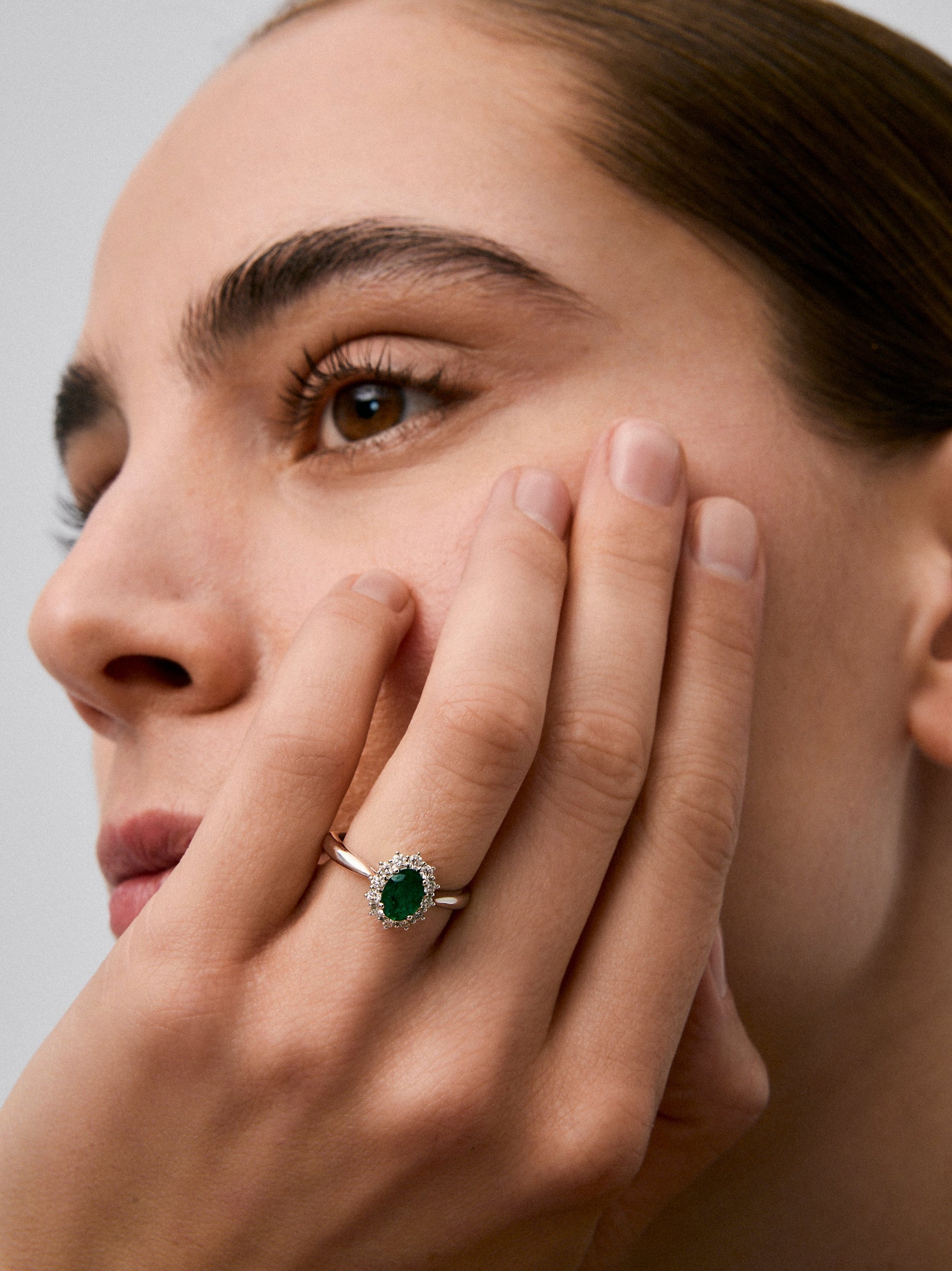 Anillo de oro blanco de 18K con esmeralda central en talla oval de 0,78 cts y orla de diamantes en talla brillante con un total de 0,42 cts