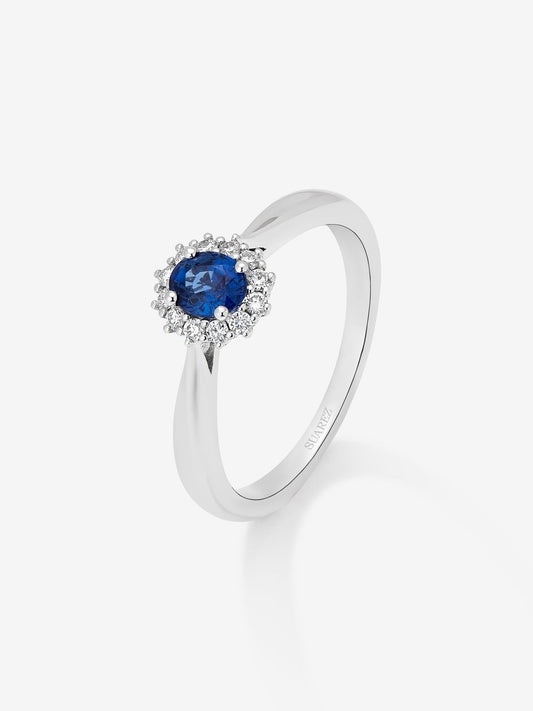 Anillo de oro blanco de 18K con zafiro azul central en talla oval de 0,25 cts y orla de diamantes en talla brillante con un total de 0,18 cts