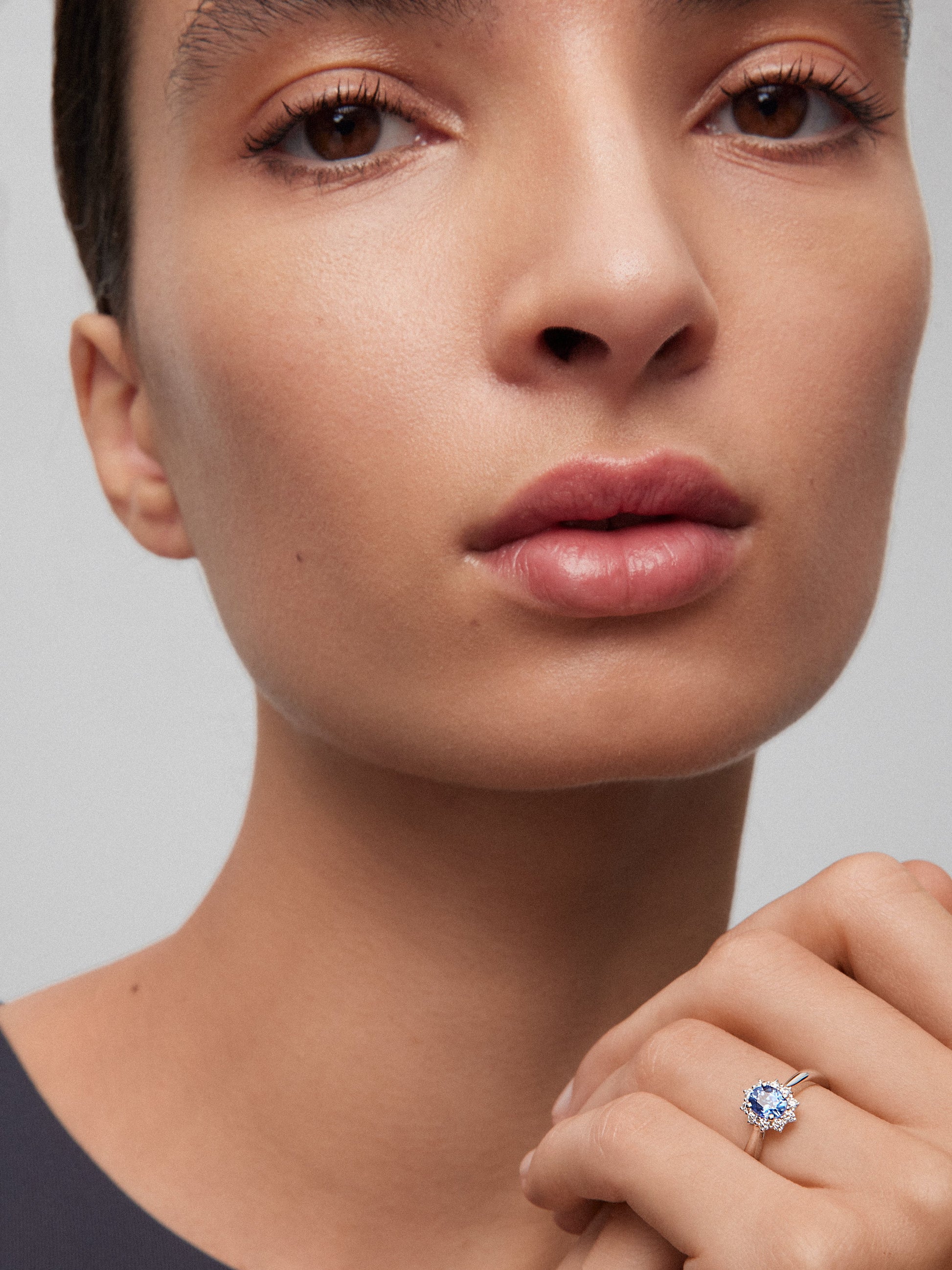 Anillo de oro blanco de 18K con zafiro azul central en talla oval de 0,4 cts y orla de diamantes en talla brillante con un total de 0,25 cts