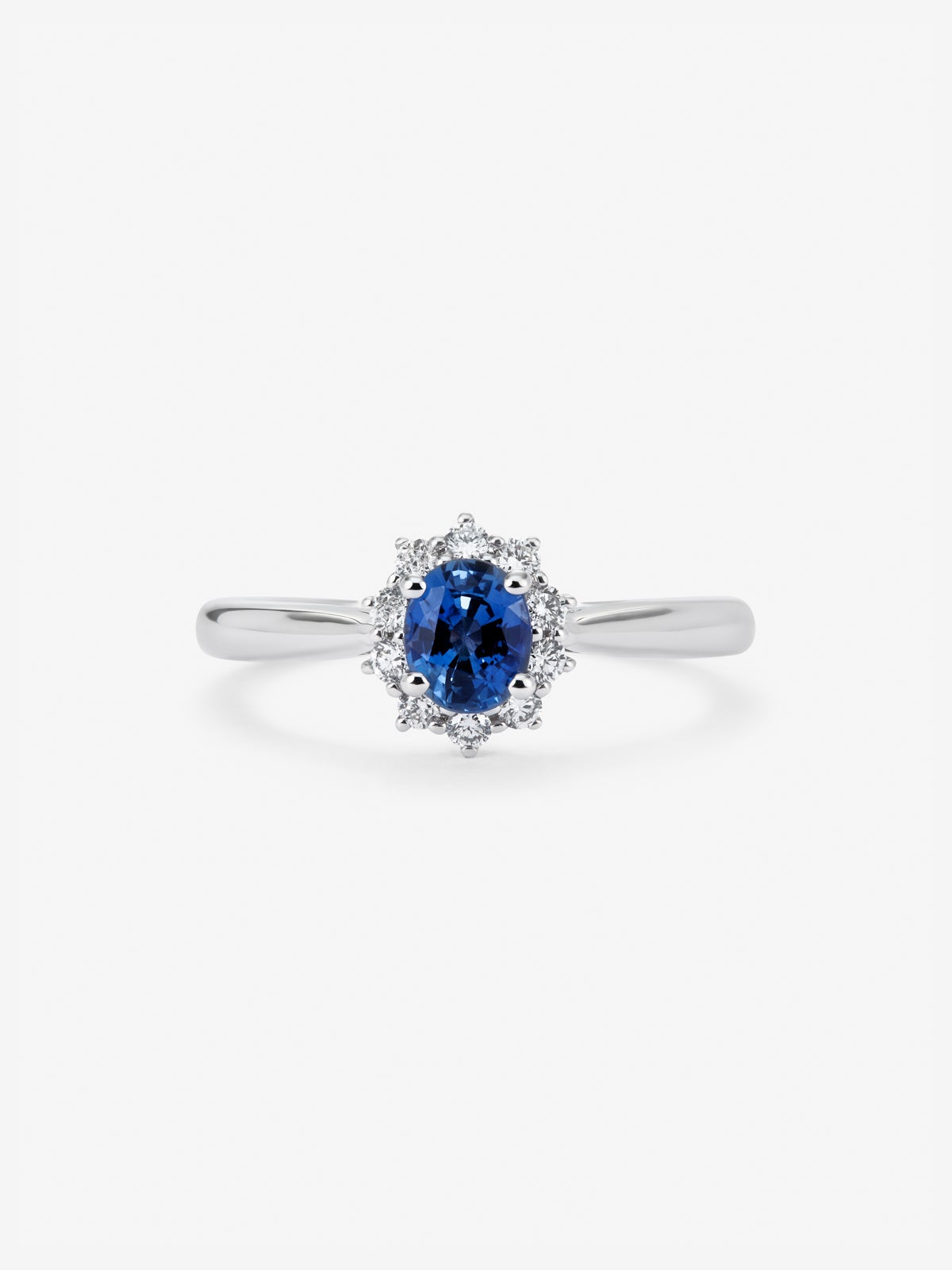 Anillo de oro blanco de 18K con zafiro azul central en talla oval de 0,40 cts y orla de diamantes en talla brillante