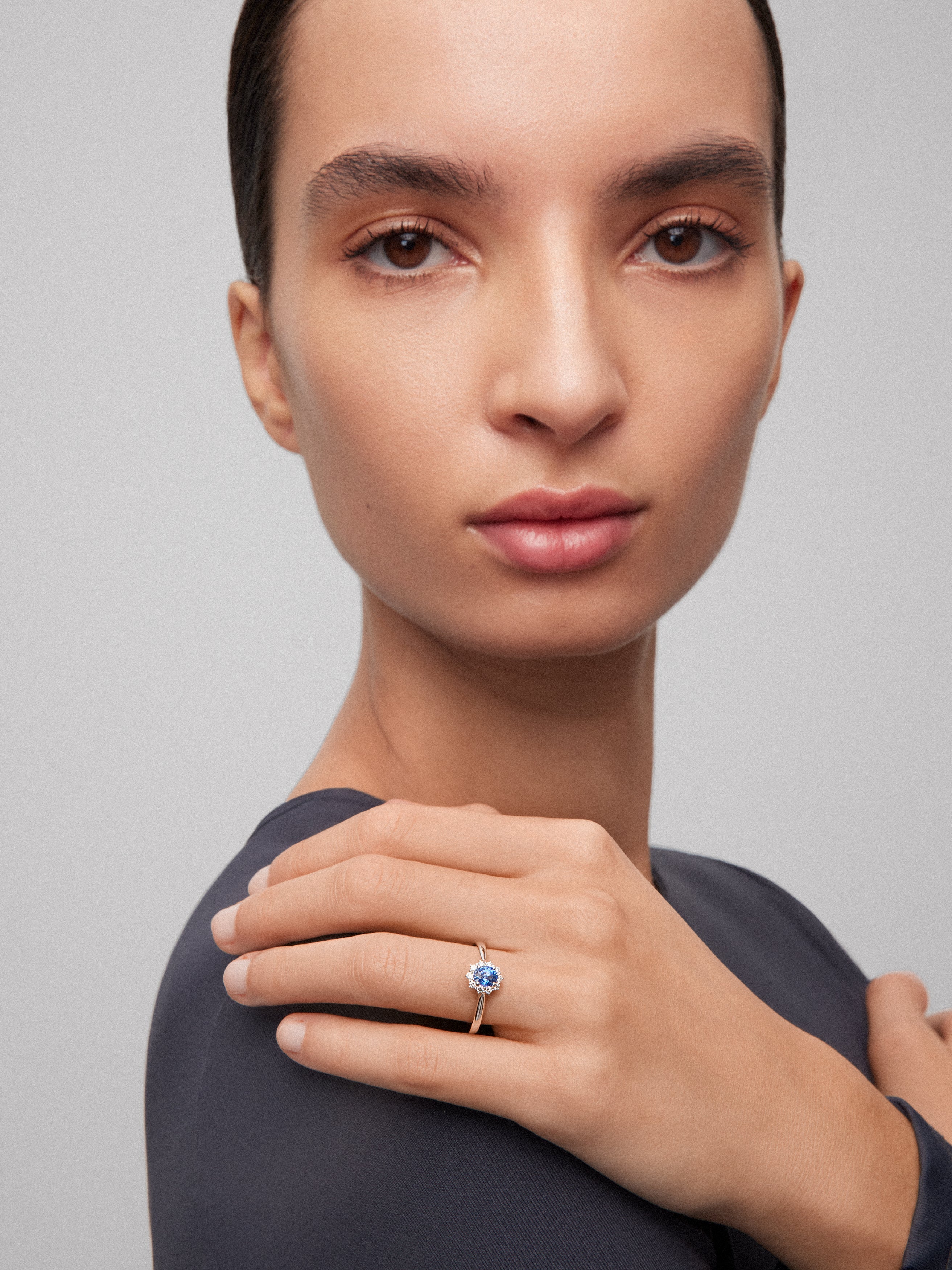 Anillo de oro blanco de 18K con zafiro azul central en talla oval de 0,30 cts y orla de diamantes en talla brillante con un total de 0,12 cts