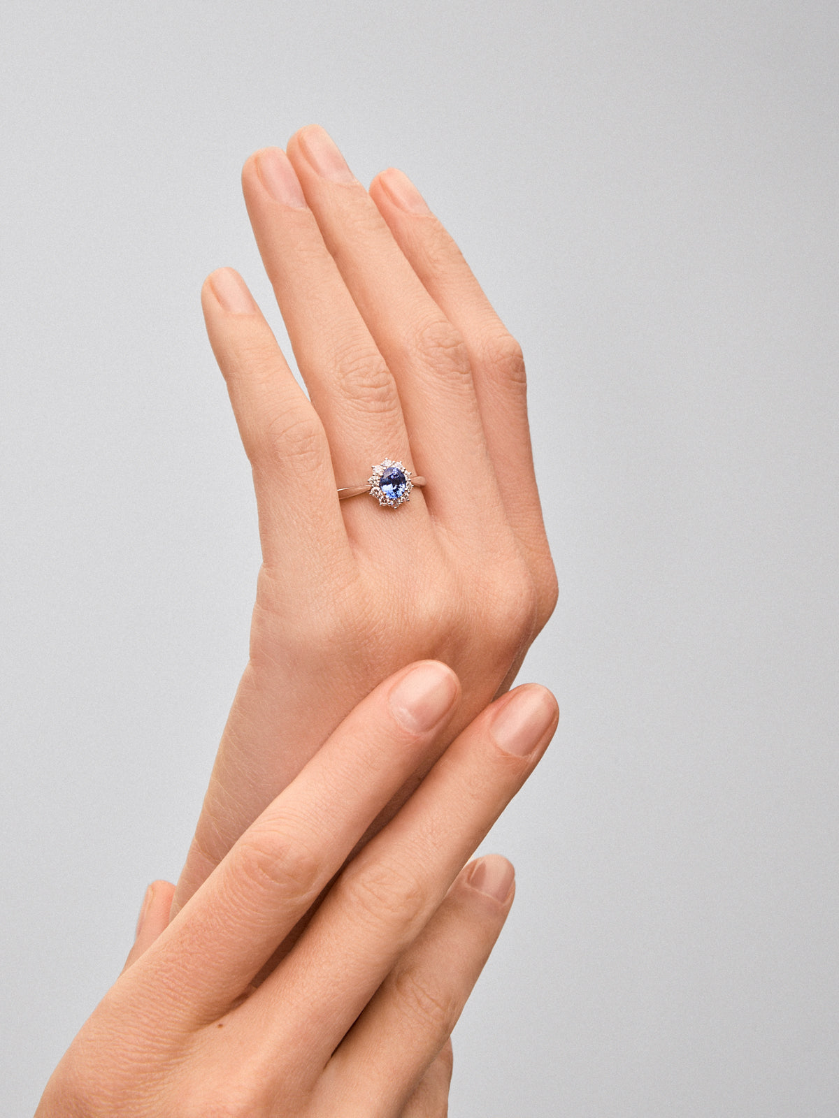 Anillo de oro blanco de 18K con zafiro azul central en talla oval de 0,4 cts y orla de diamantes en talla brillante con un total de 0,25 cts