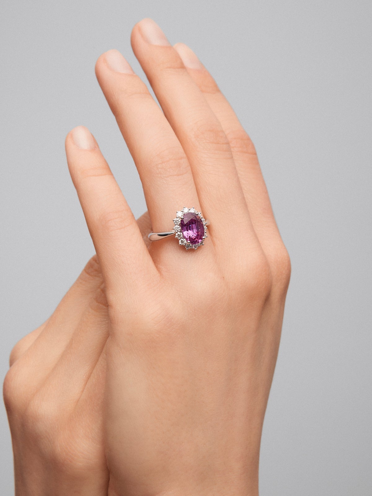 Anillo de oro blanco de 18K con zafiro rosa en talla oval de 0,55 cts y 12 diamantes en talla brillante con un total de 0,1 cts