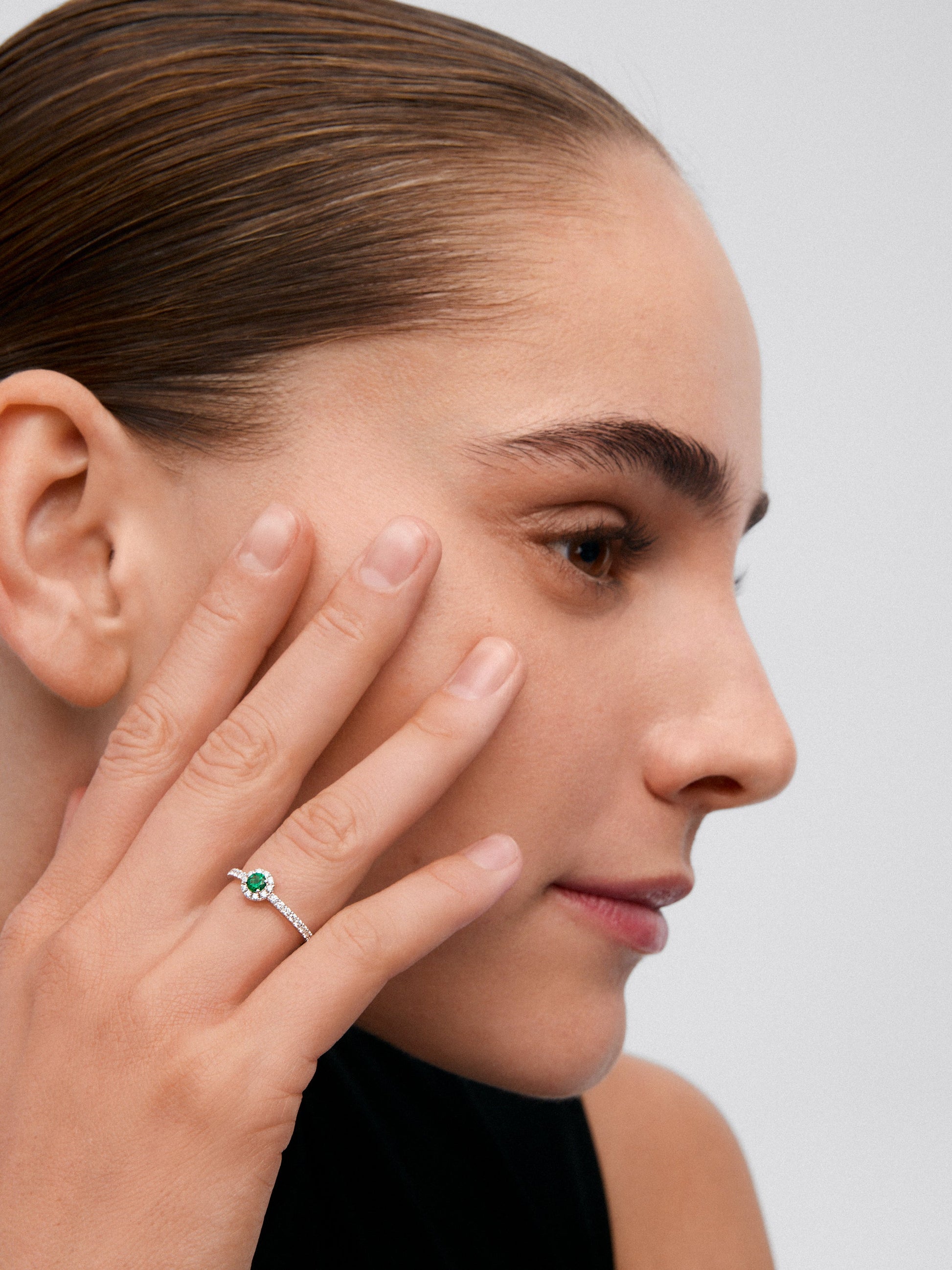 Anillo de oro blanco de 18K con esmeralda en talla brillante de 0,1 cts y brazo y orla de diamantes en talla brillante con un total de 0,20 cts