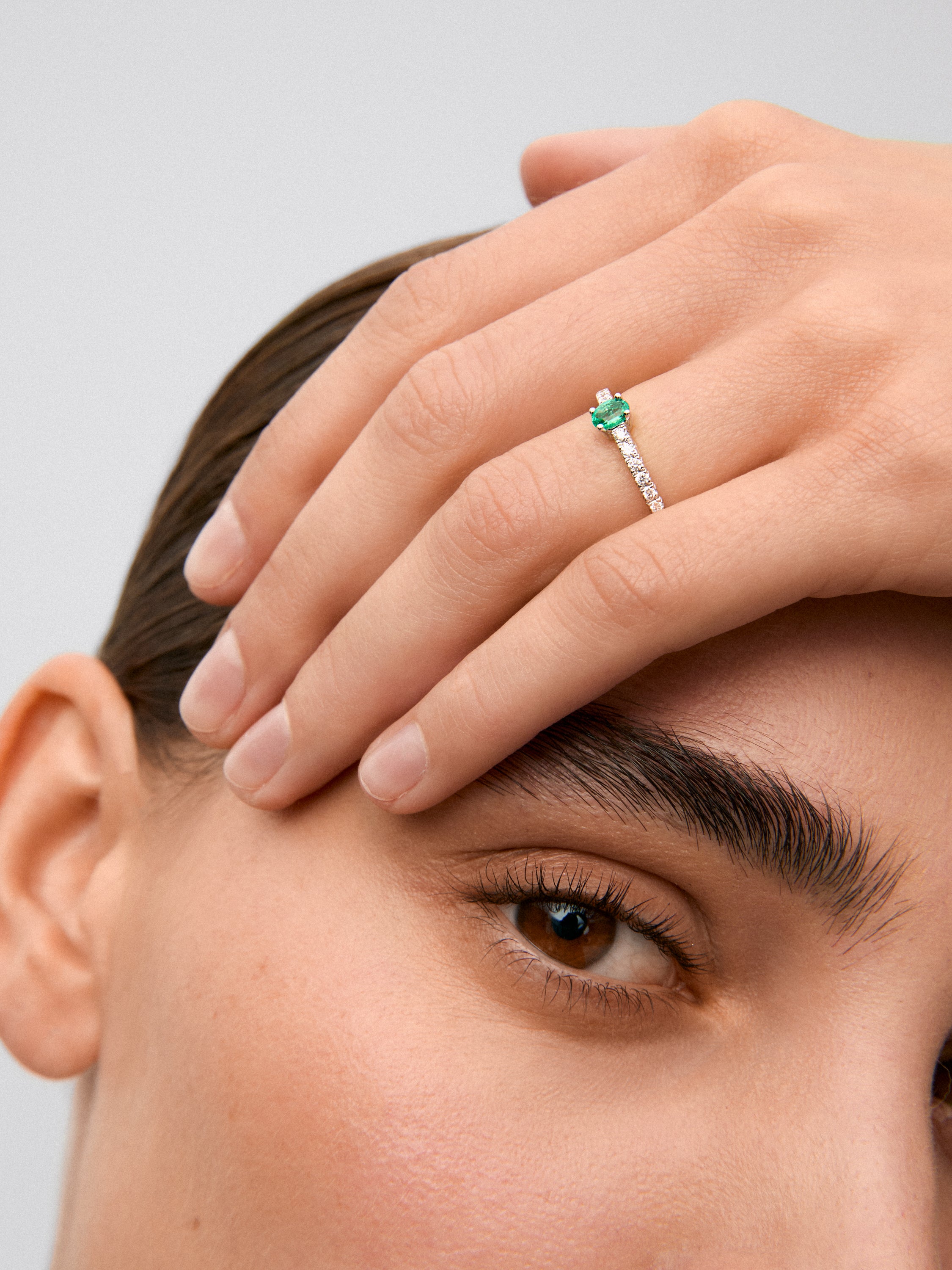 Anillo de oro blanco de 18K con una esmeralda verde en talla oval de 0,20 cts y 16 diamantes en talla brillante con un total de 0,21 cts