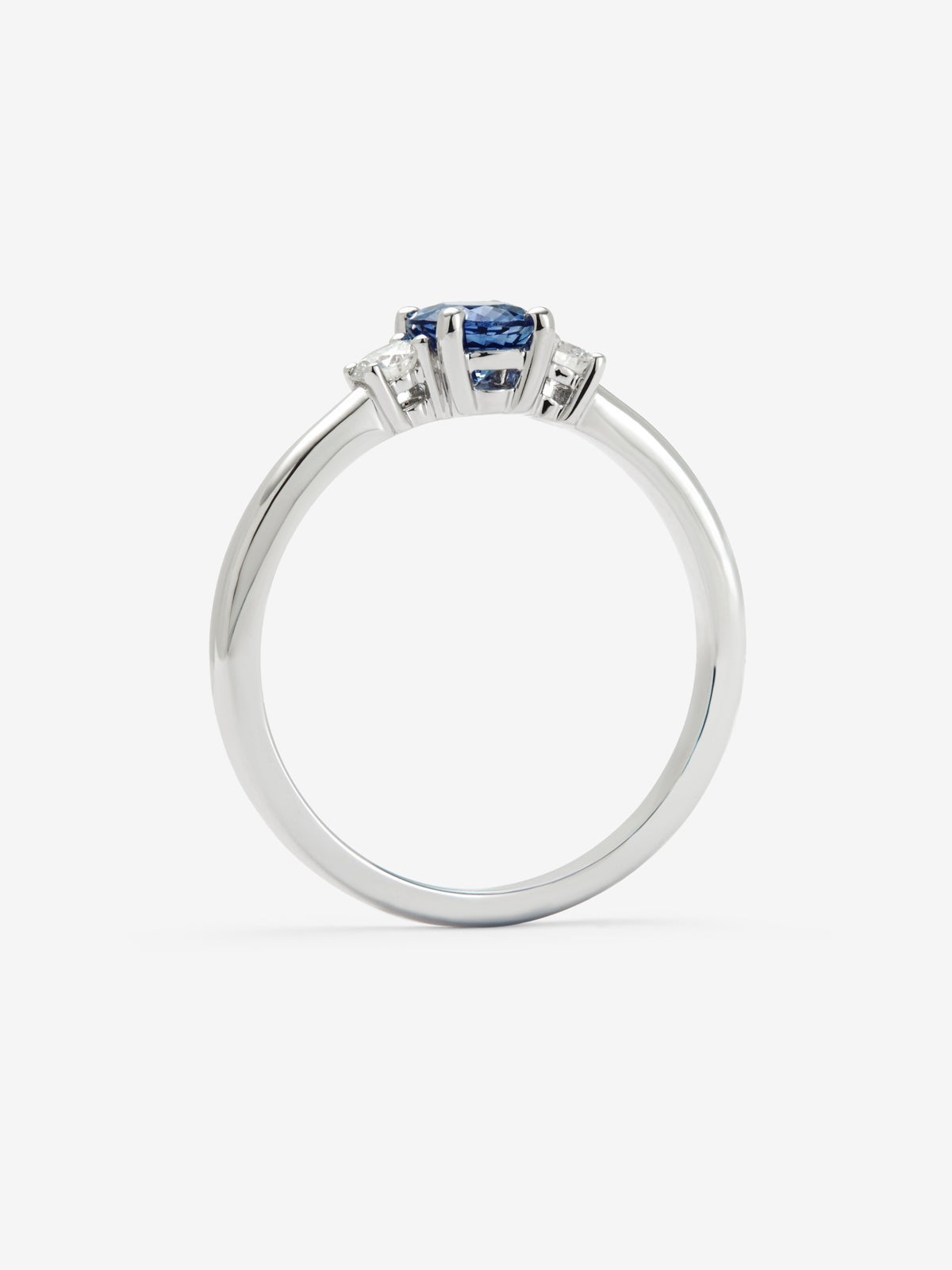 Anillo tresillo de oro blanco de 18K con zafiro azul en talla oval de 0,69 cts y 2 diamantes en talla brillante con un total de 0,16 cts