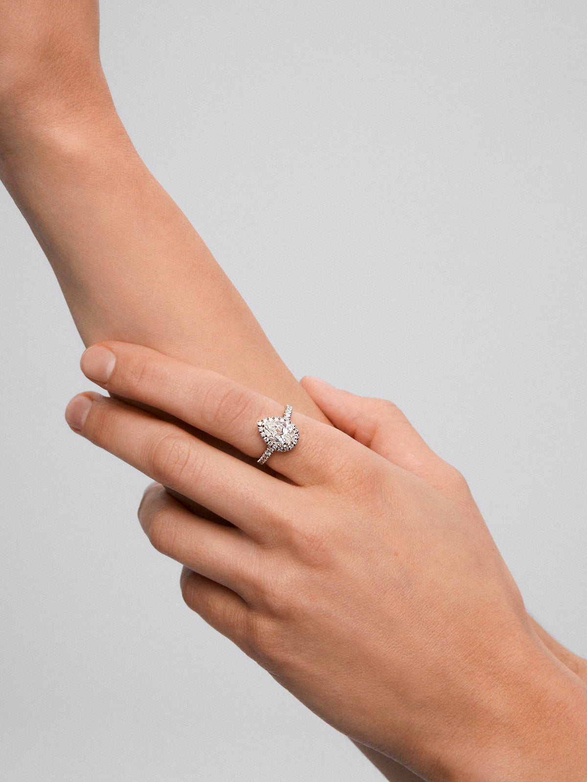Anillo de oro blanco de 18K con diamante central en talla pera y orla y brazo de diamantes 