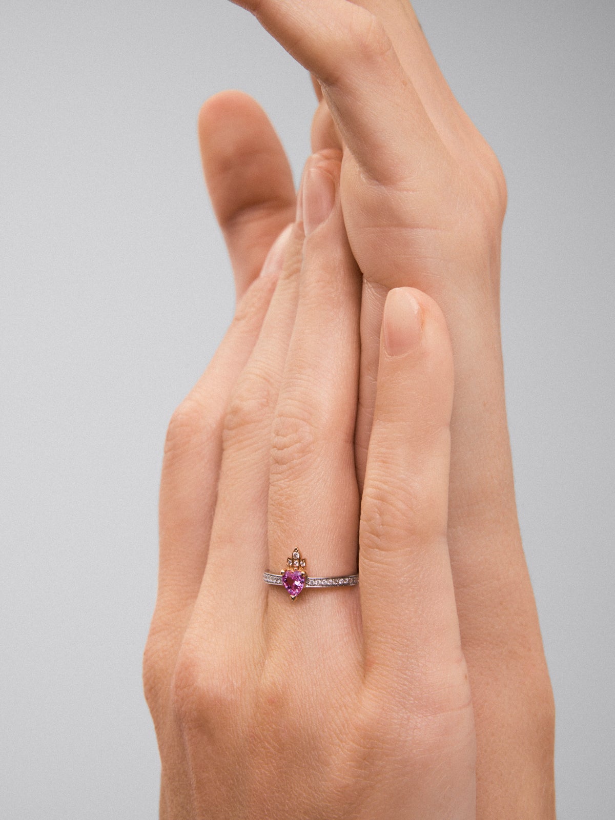 Anillo de oro blanco y rosa de 18K con zafiro rosa en talla corazón de 0,4 cts y 26 diamantes en talla brillante con un total de 0,132 cts