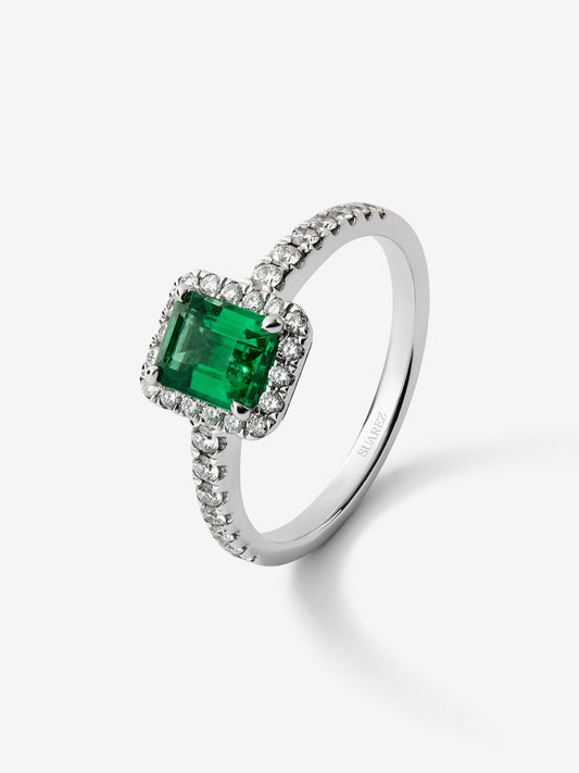 Anillo de oro blanco de 18K con esmeralda en talla esmeralda de 0,70cts y orla y brazo de 32 diamantes en talla brillante 
