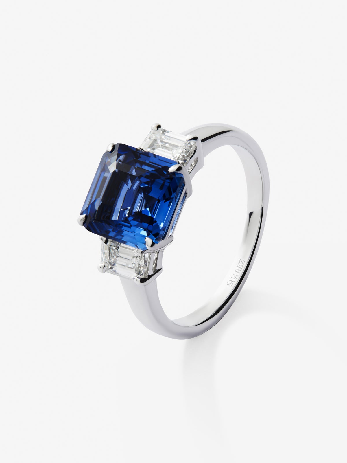 Anillo tresillo de oro blanco de 18K con zafiro azul en talla esmeralda de 4,07 cts y 2 diamantes en talla esmeralda con un total de 0,81 cts