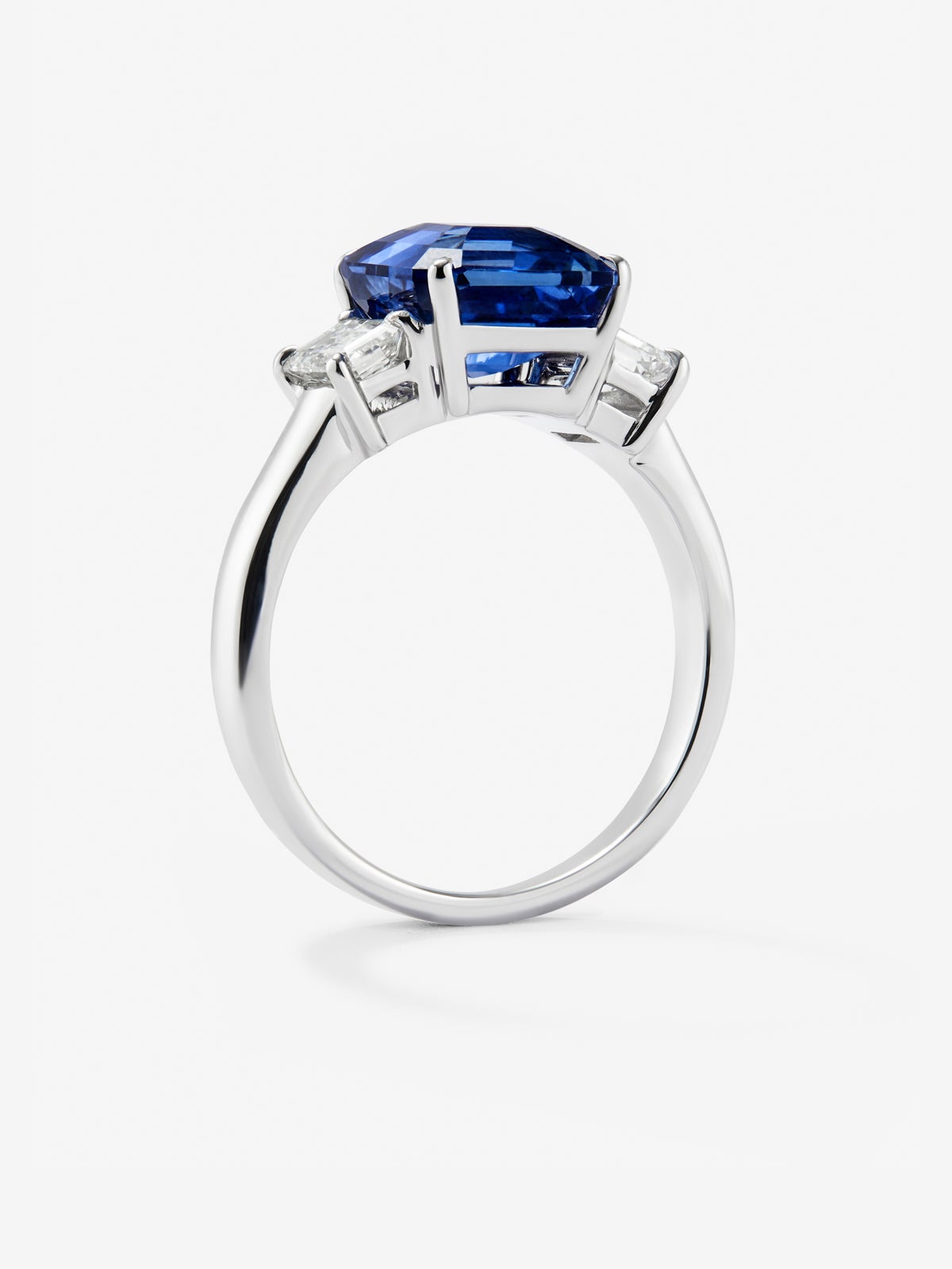 Anillo tresillo de oro blanco de 18K con zafiro azul en talla esmeralda de 4,07 cts y 2 diamantes en talla esmeralda con un total de 0,81 cts