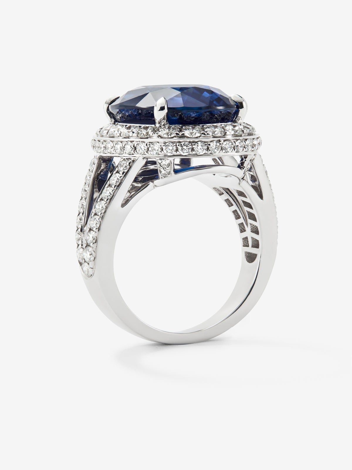 Anillo de oro blanco de 18K con zafiro azul royal en talla oval de 12,64 cts y orla y brazo de 93 diamantes con un total de 1,74 cts