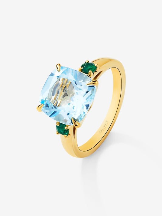 Anillo tresillo de oro amarillo de 18K con topacio azul sky en talla cushion de 4,88 cts y 2 esmeraldas verdes en talla brillante