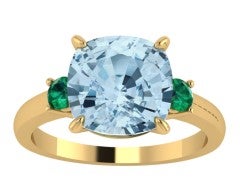 Anillo de oro amarillo de 18K con topacio azul sky en talla cushion y esmeraldas en talla brillante con un total de 0,1 cts