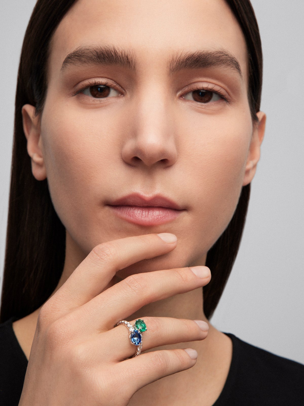 Anillo tú y yo de oro blanco de 18K con zafiro azul en talla oval de 1,75 cts, esmeralda en talla oval de 1,28 cts y 12 diamantes en talla brillante con un total de 0,25 cts