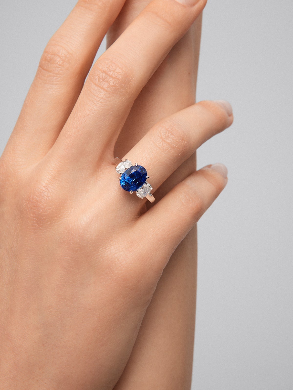Anillo tresillo de oro blanco de 18K con zafiro azul royal en talla oval de 4,05 cts y 2 diamantes en talla oval con un total de 1,05 cts