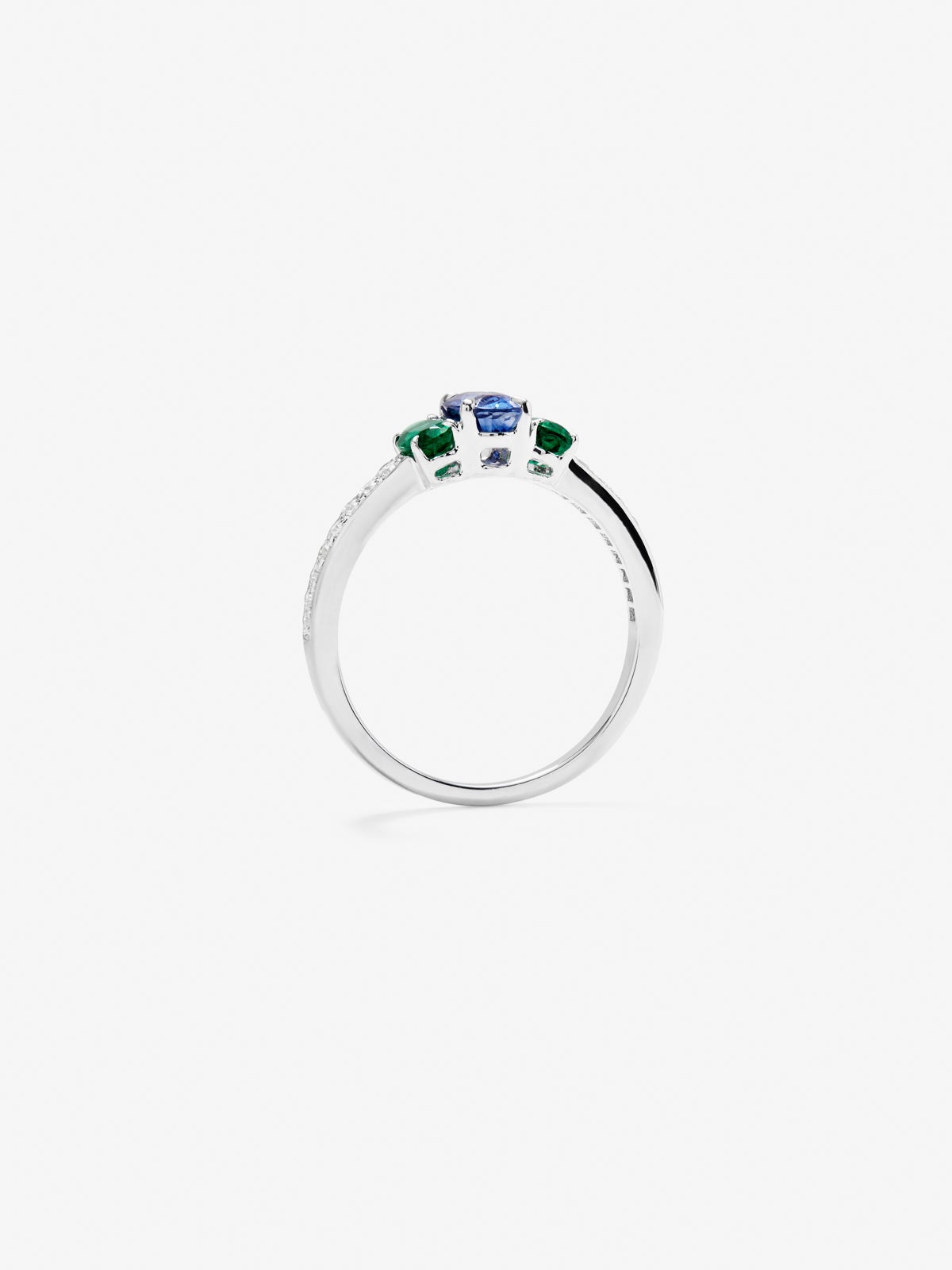Anillo tresillo de oro blanco de 18K con zafiro azul en talla oval de 0,7 cts, esmeraldas verdes en talla oval de 0,41 cts y diamantes blancos en talla brillante de 0,115 cts