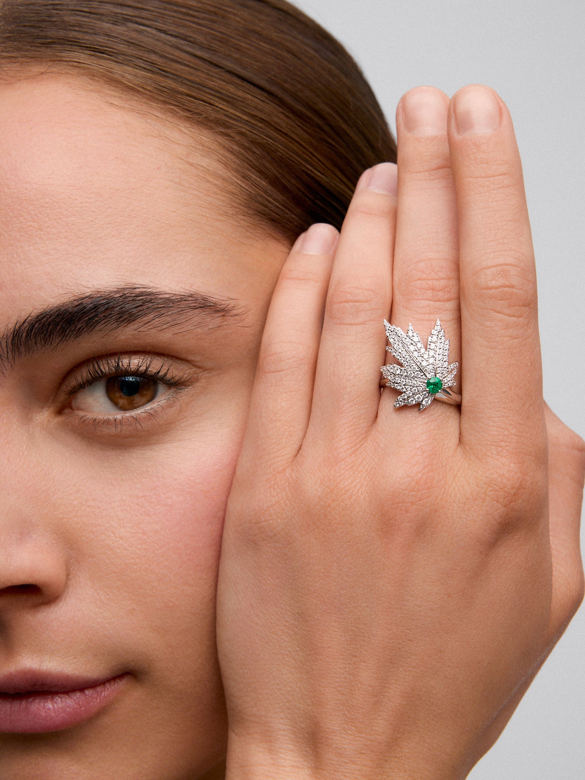 Anillo de oro blanco de 18K con esmeralda central de 0,16 cts, pavé de diamantes y forma de hoja de arce