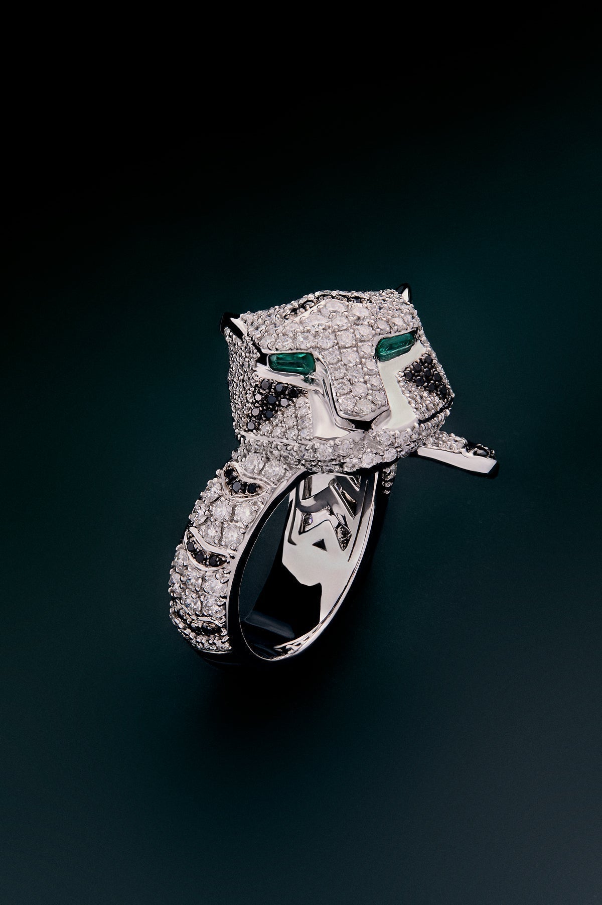 Anillo de oro blanco de 18K con 278 diamantes blancos en talla brillante con un total de 1,87 cts, 55 diamantes negros en talla brillante con un total de 0,25 cts, y 2 esmeraldas en talla trapecio con un total de 0,13 cts con forma de tigre