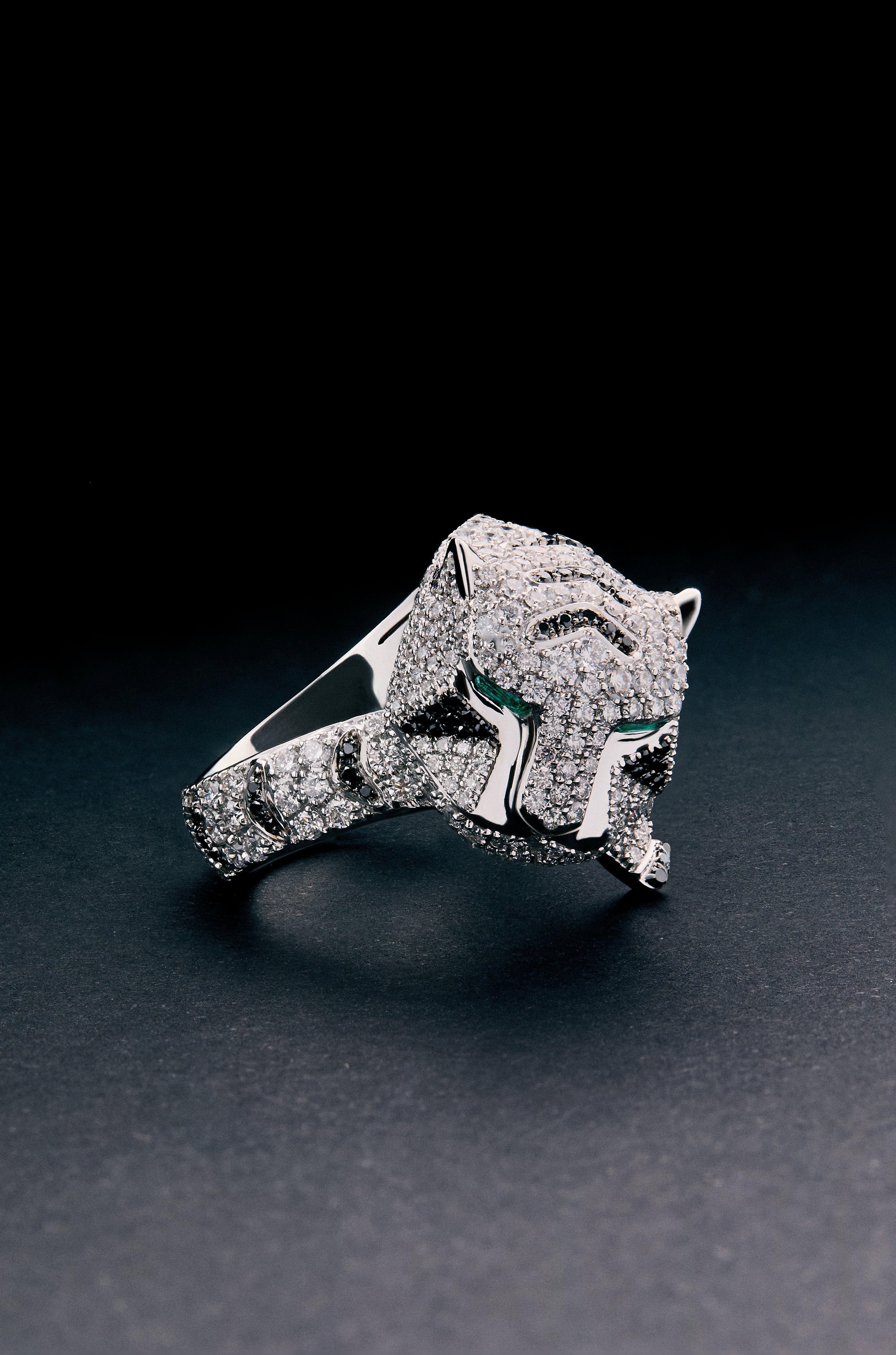 Anillo de oro blanco de 18K con 278 diamantes blancos en talla brillante con un total de 1,87 cts, 55 diamantes negros en talla brillante con un total de 0,25 cts, y 2 esmeraldas en talla trapecio con un total de 0,13 cts con forma de tigre