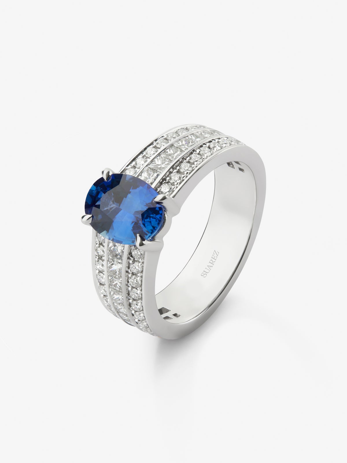 Anillo de oro blanco de 18K con zafiro azul royal en talla oval de 2,53 cts, 44 diamantes en talla brillante con un total de 0,37 cts y 22 en talla princesa con un total de 0,58 cts
