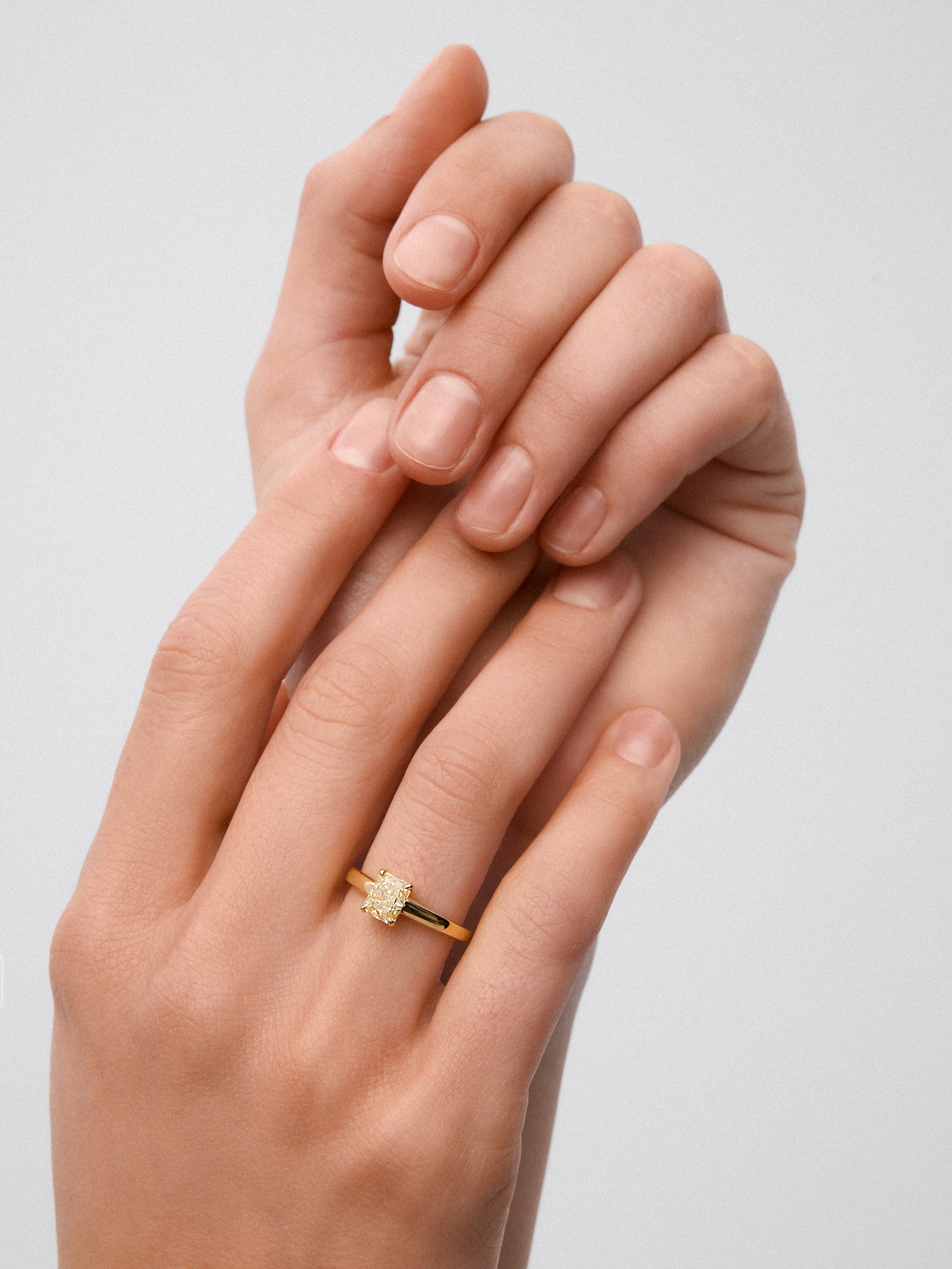 Anillo solitario de oro amarillo de 18K con diamante central Fancy Yellow en talla radiant de 0,78 cts