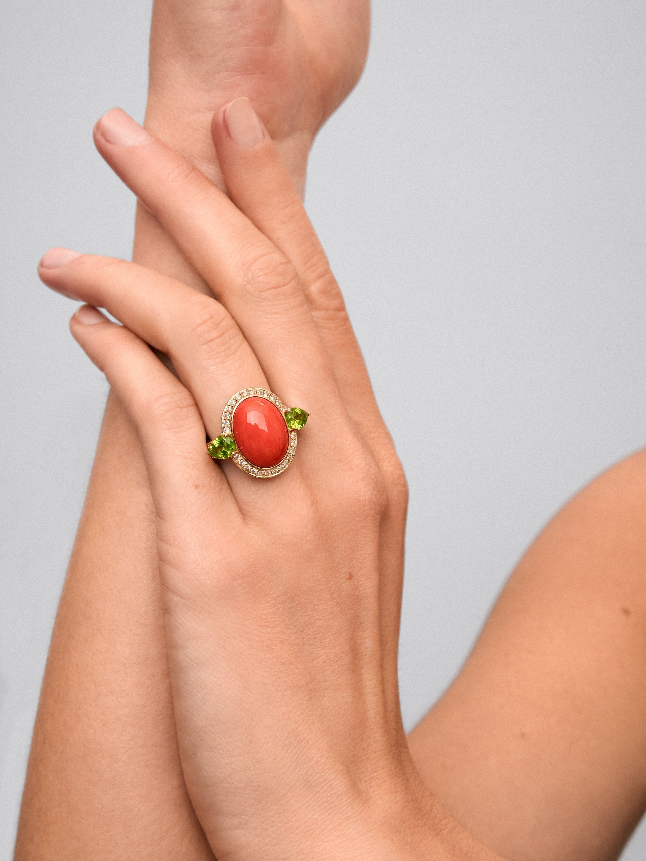 Anillo de oro amarillo de 18K con coral en talla oval, 2 peridotos verdes en talla pera y 30 diamantes en talla brillante con un total de 0,3 cts