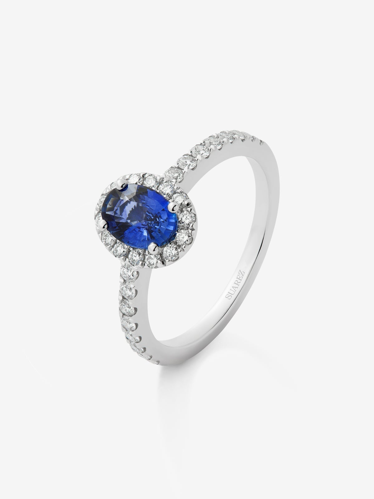 Anillo de oro blanco de 18K con zafiro azul en talla oval de 0,89 cts y orla de diamantes en talla brillante con un total de 0,34 cts